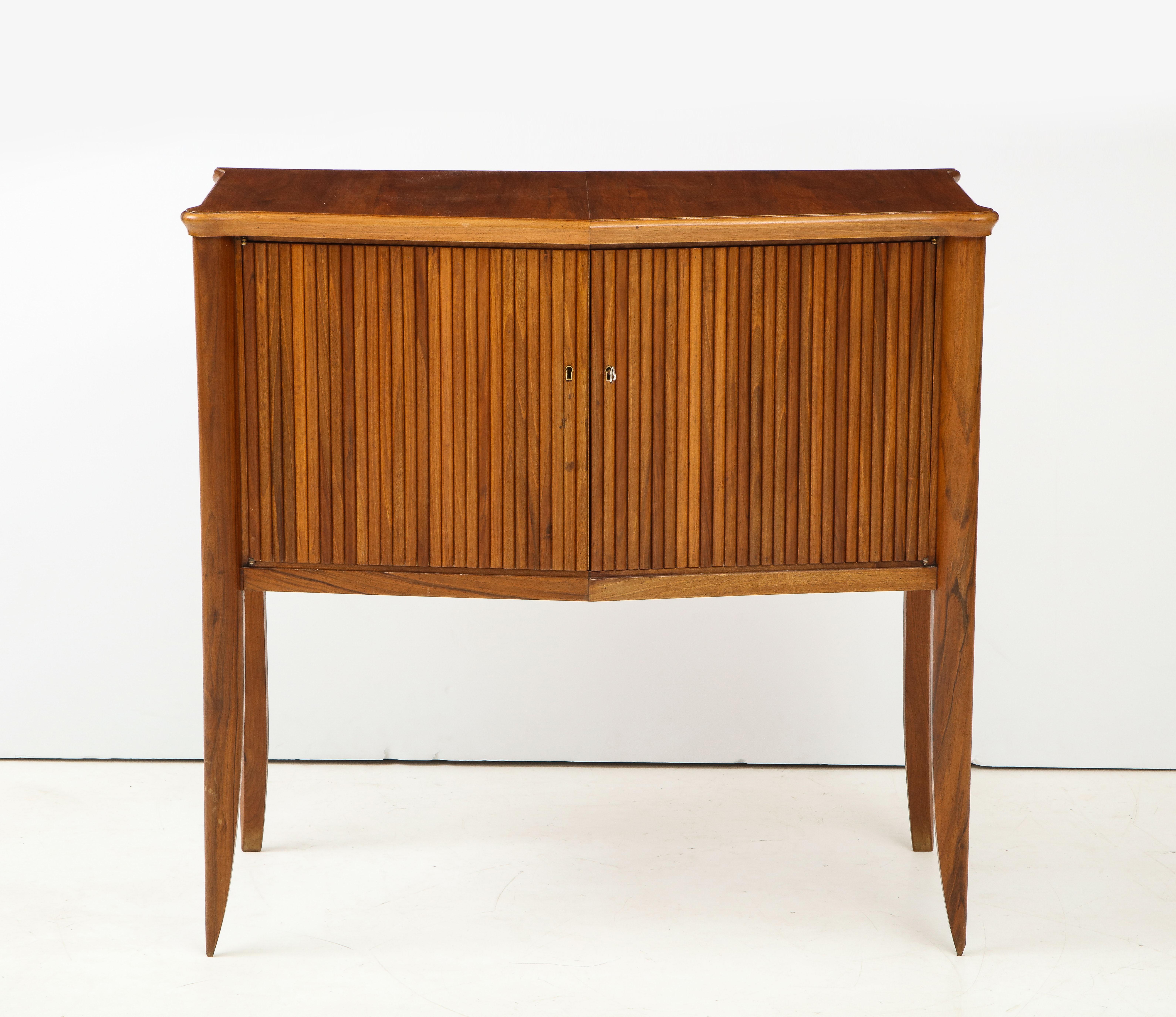 An Italian walnut two-door cabinet with ribbed carving, supported on elegantly tapered legs, the interior fitted with one shelf.
Italy, circa 1940
Size: 39 1/2