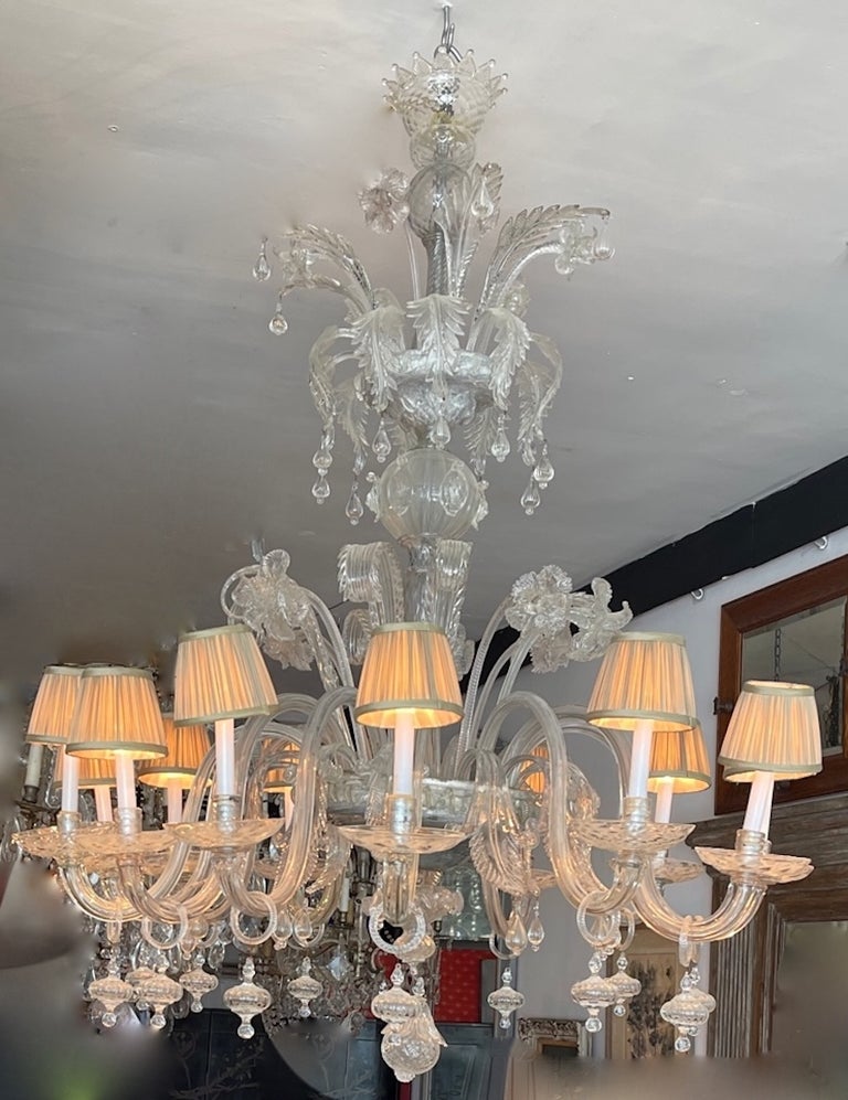 This is beautiful 12 arm 12 light Murano transparent glass chandelier. We have rewired it for use in the United States and we have added a small pleated shades for each light.