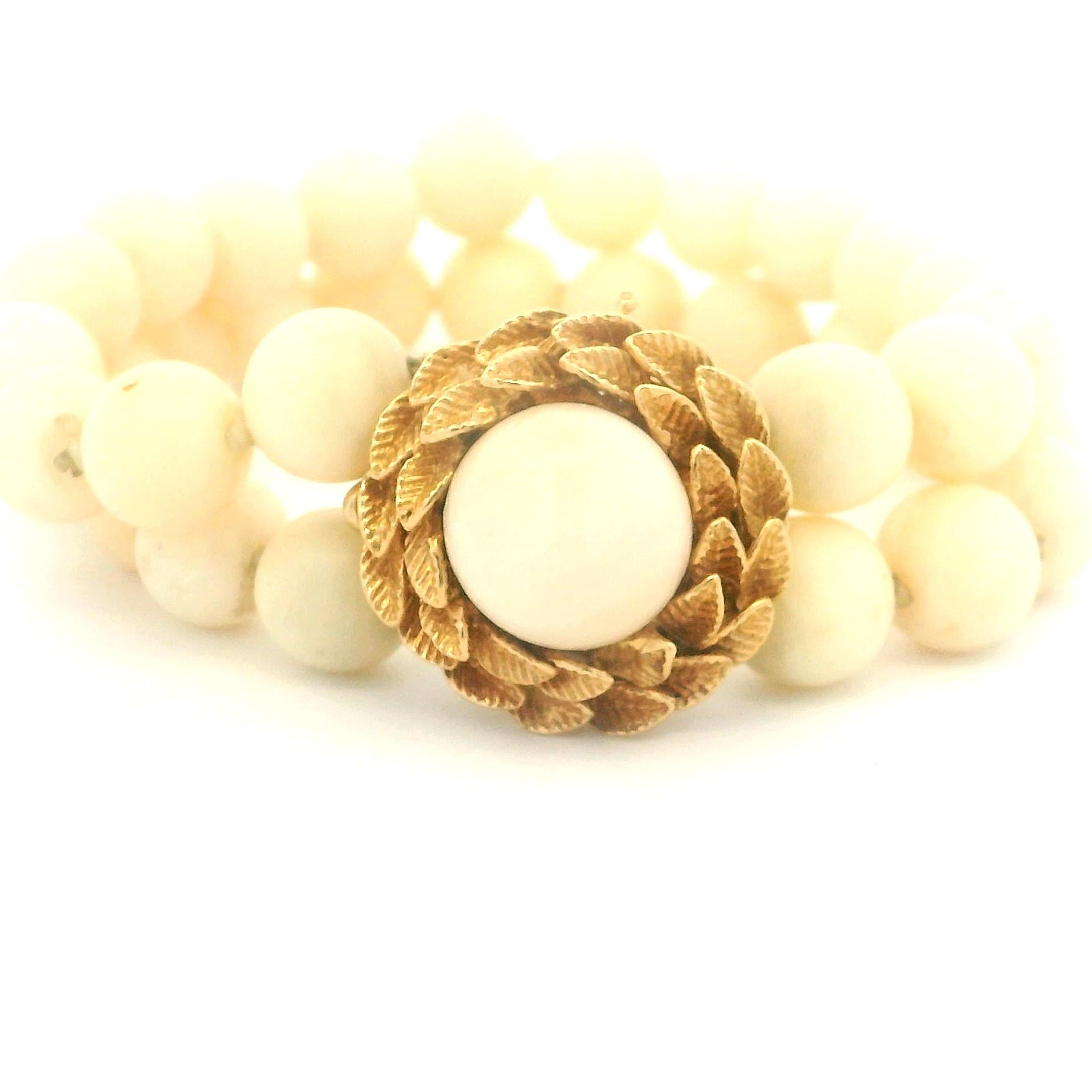 Una pulsera refinada y atemporal de mediados de siglo, compuesta por cuentas de coral natural Piel de Ángel en un tono rubor suave y cremoso. La pulsera está diseñada como una doble hilera de cuentas de coral redondas y lisas, que se gradúan