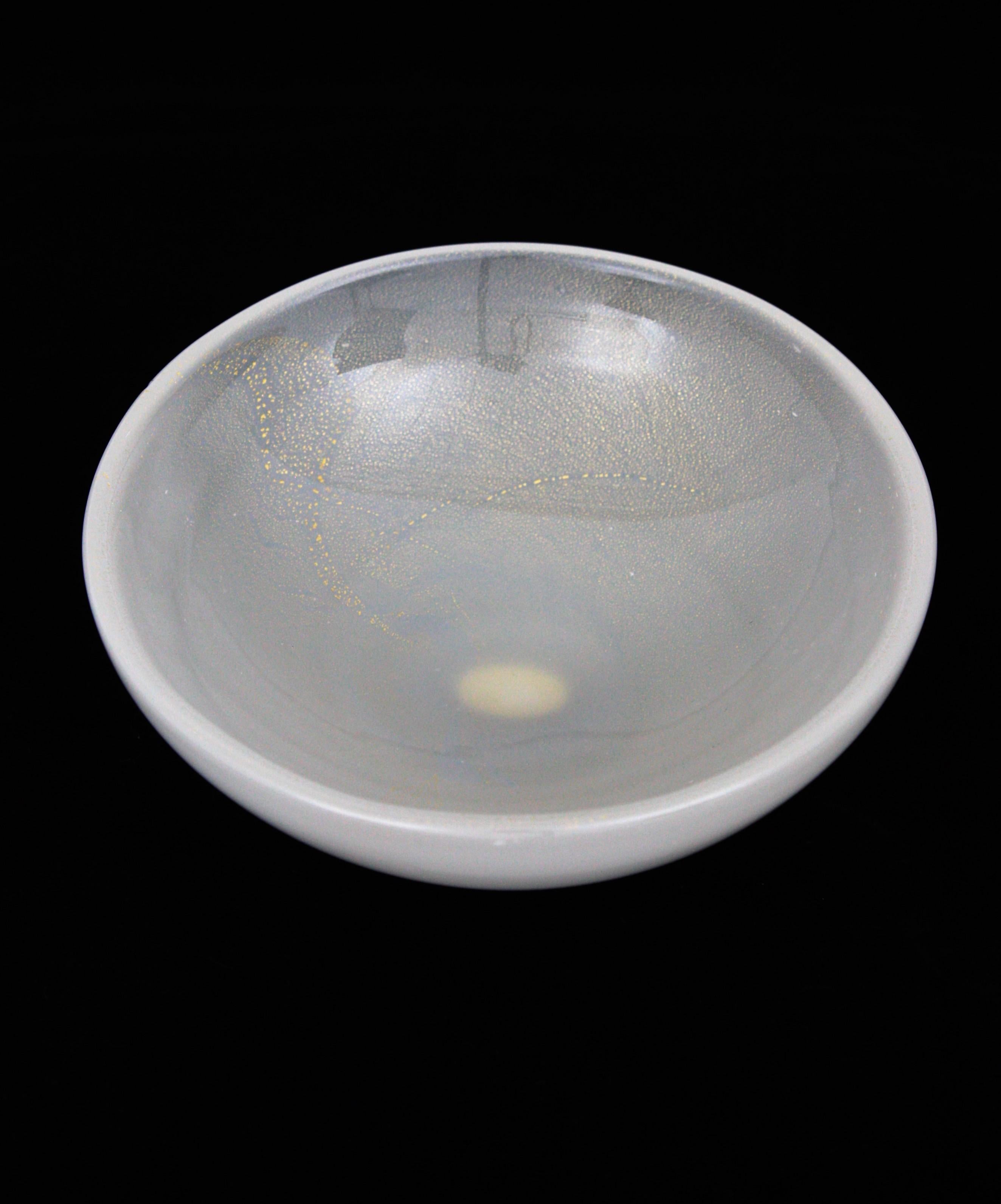 Coupe ronde en verre de Murano blanc opalescent avec poussière d'or fabriquée par Archimede Seguso. Italie, années 1950.
Ce magnifique bol en verre soufflé à la bouche de Murano peut être utilisé comme bol à bagues, vide-poche, bol à bonbons ou