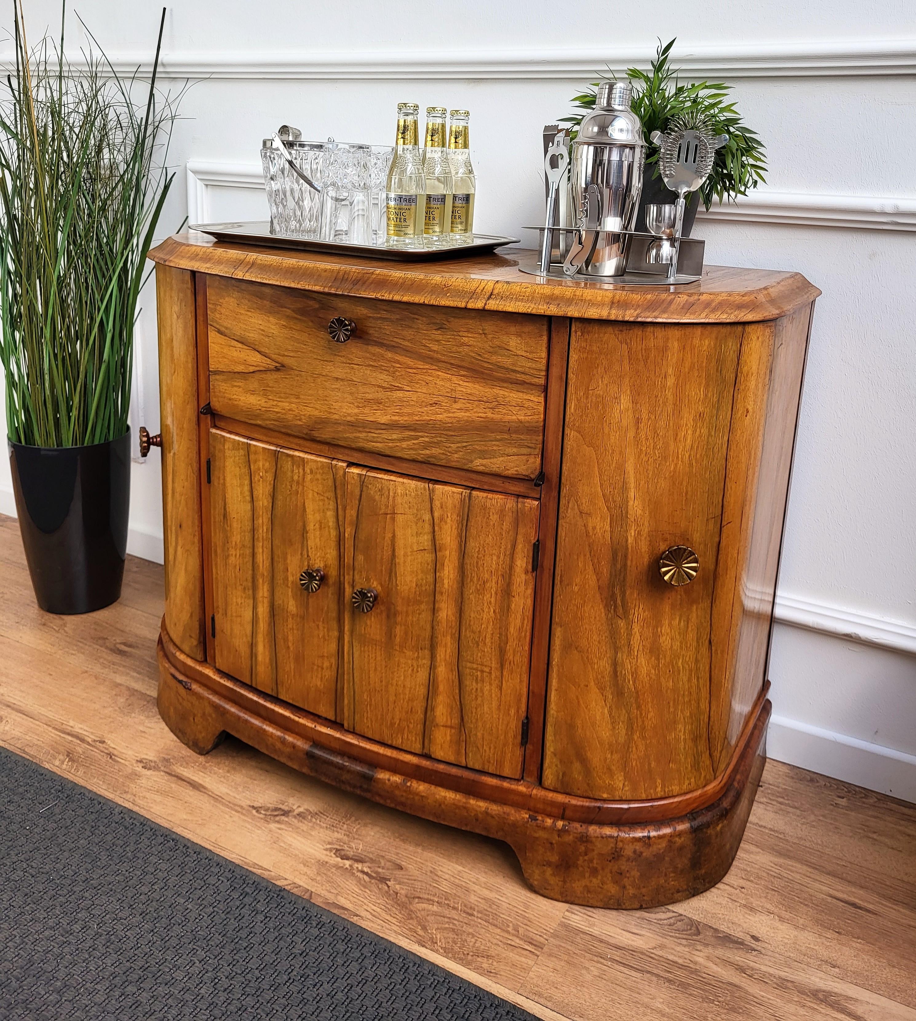 Very elegant Italian Art Deco Mid-Century Modern drinks dry bar cabinet with beautiful walnut wood, two side doors and two central compartments with great wooden decor craftmanship and brass handles. 
When opened, on the right and left side an