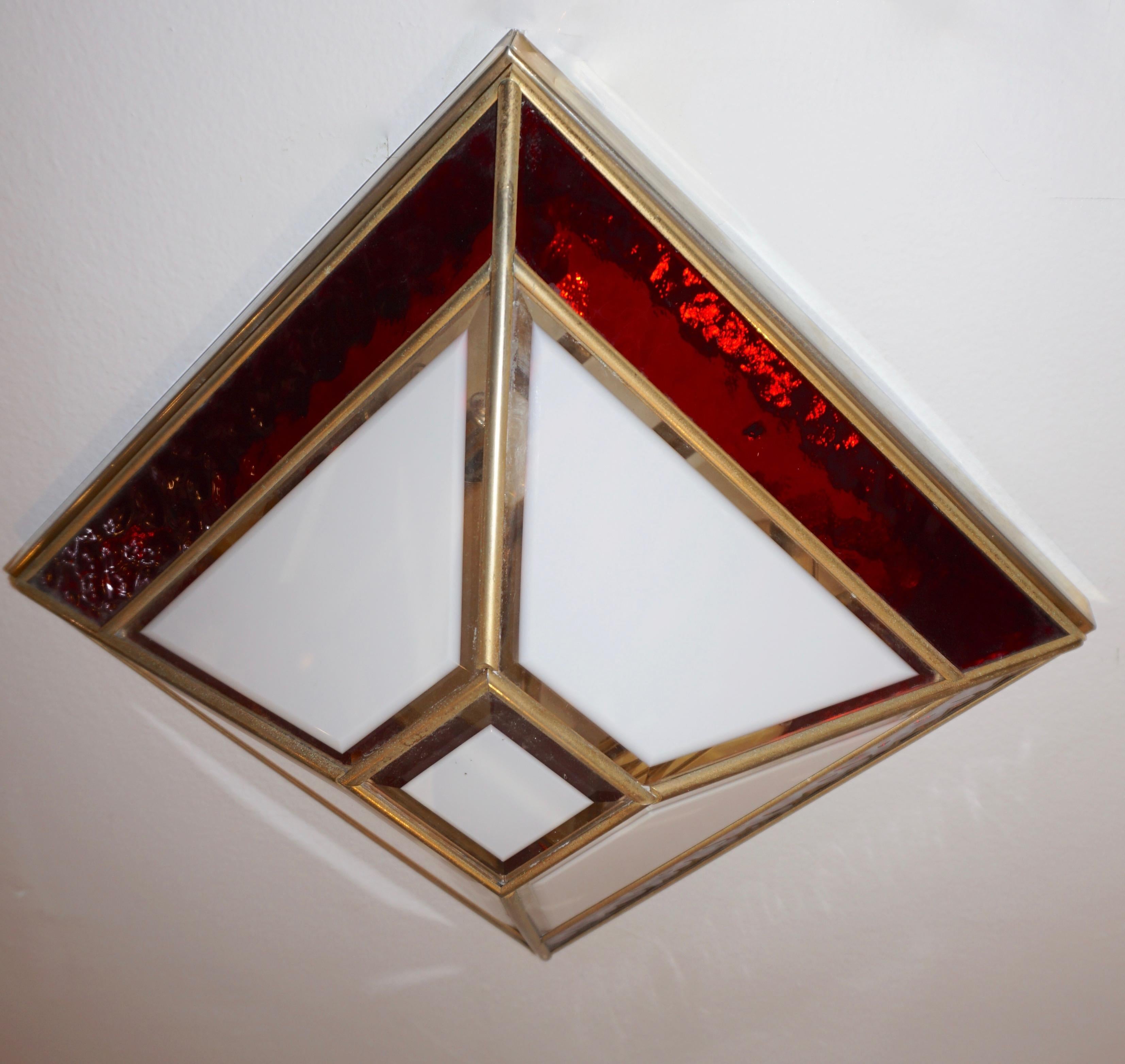 Italian 1950s pair of geometric modern design wall lights of Art Deco style, entirely handcrafted, high quality of details: the pyramid shaped brass structure encloses a red border in textured glass and a dome with 5 white satin frosted glass panels
