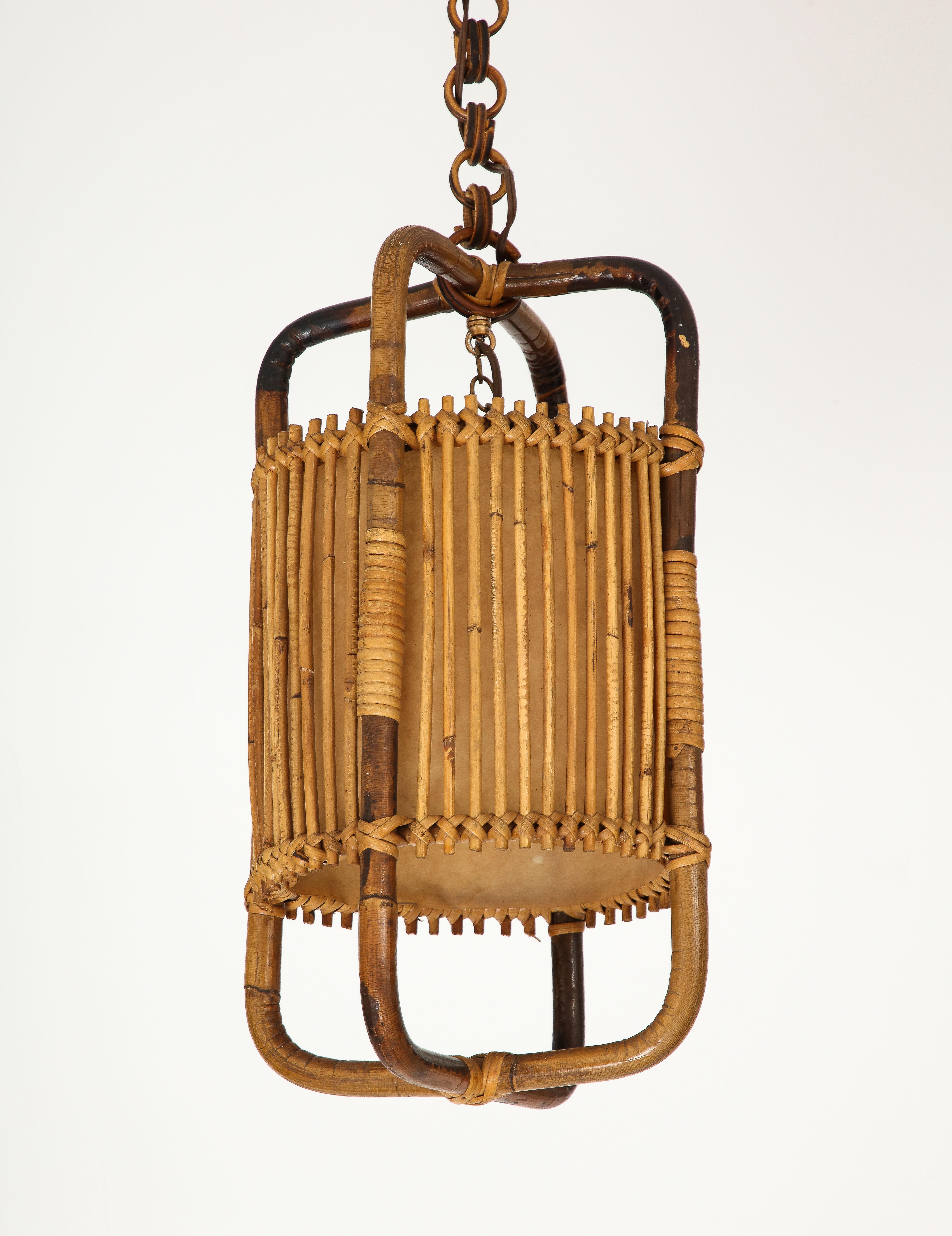 Italian 1950's charming bamboo and rattan lantern / pendant, entirely handcrafted with rattan, bamboo and wicker. The fixture is supported by a chain with round rattan links and rattan circular canopy; all original. With inner parchment to diffuse a