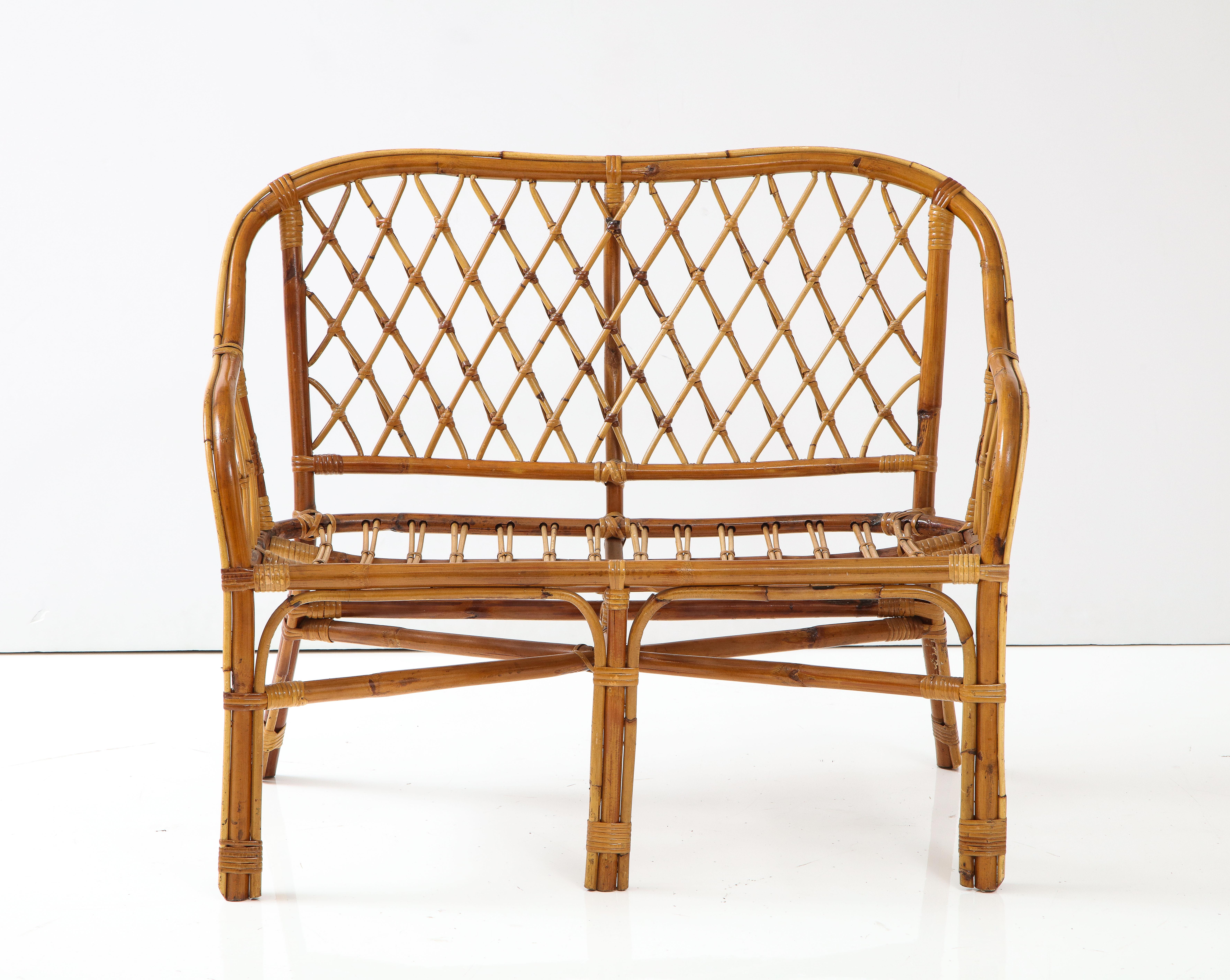 Italian 1950's charming bamboo settee with sloped arms and cross hatch motif within the arms and on the back rest, the bamboo coloring in a beautiful warm variation of warm brown to lighter brown. 
Italy, circa 1950.
Size: 33