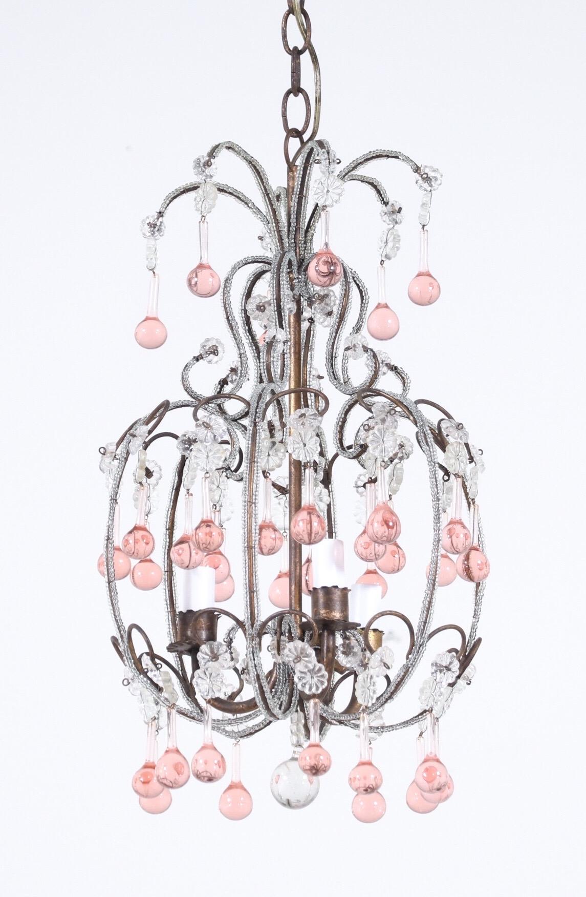 Beautiful, 1950s Italian gilt-iron and crystal beaded chandelier with pink Murano drops.

The chandelier consists of crystal beaded scrolled and gilded iron frame with pink Murano glass drops. The chandelier is wired and in working condition.