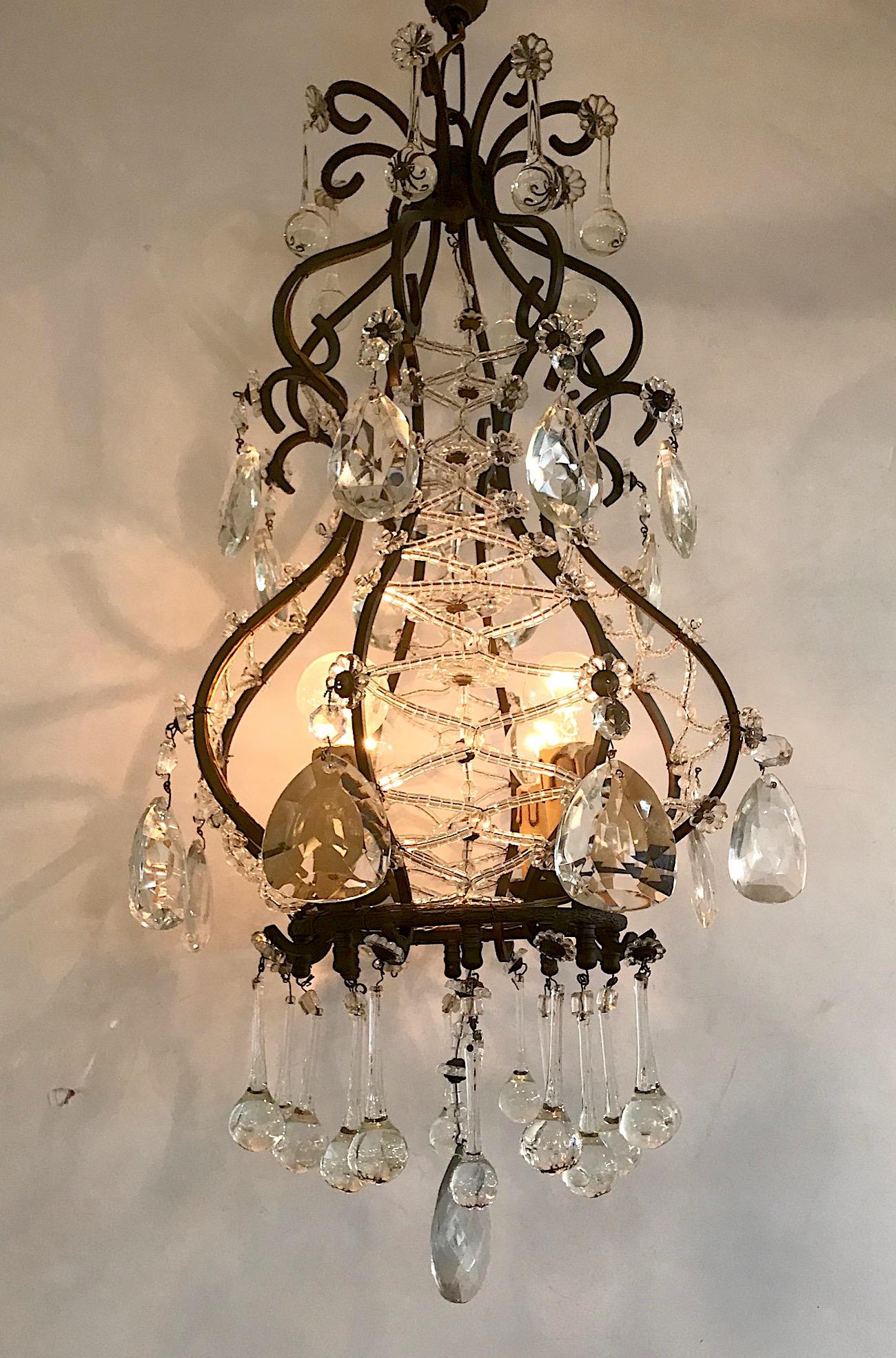 A stylish and charming 1950s Italian chandelier in patinated black iron with crystal and glass accents. The chandelier is comprised of 8 vertical scrolled iron supports. Four pair are wired in a criss cross pattern with handmade glass beads allowing
