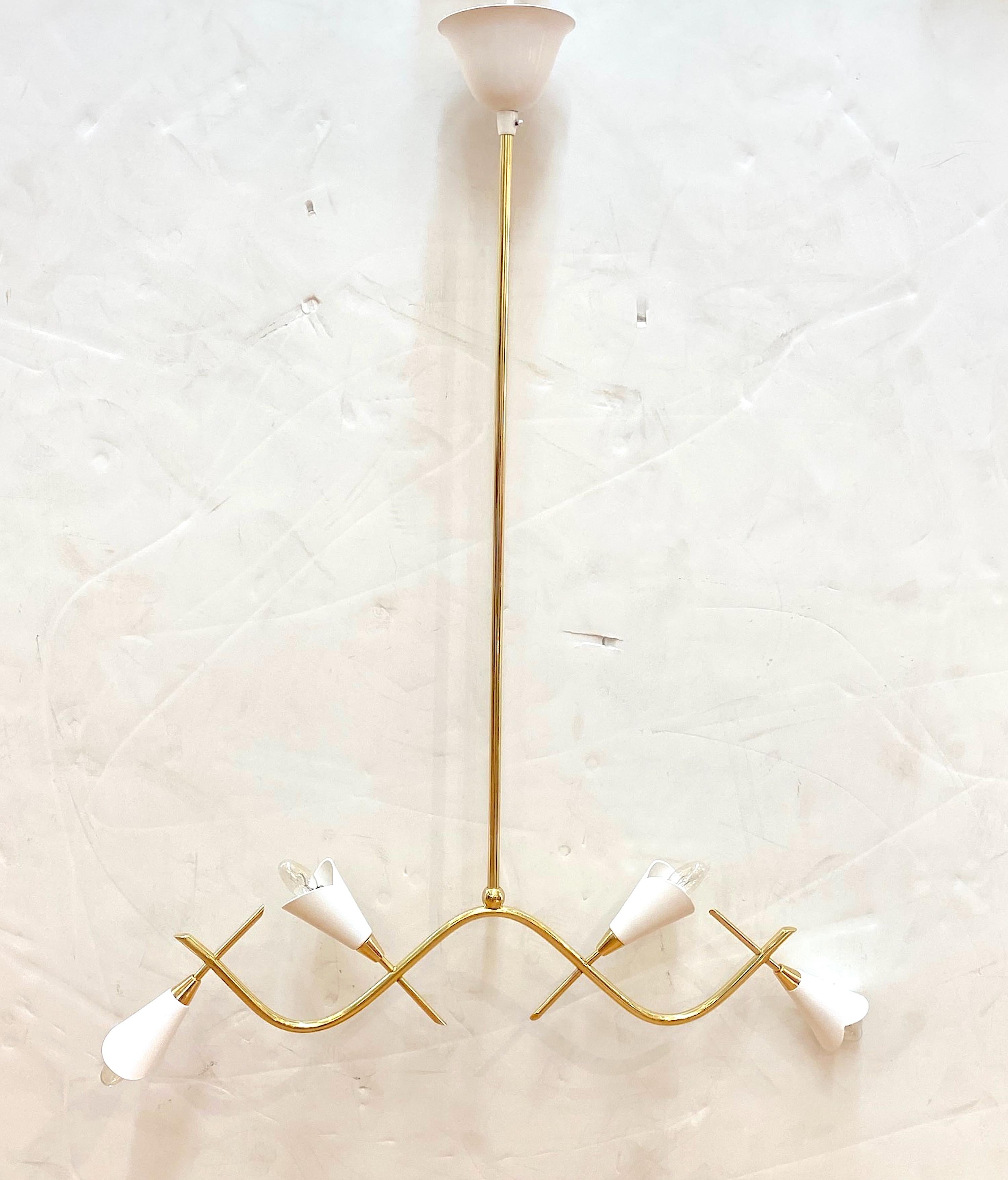 A lovely Italian 1950s modern chandelier in brass and white enamel. The design is horizontal in the fact that the four shades with sockets are in a line. Perfect for over a rectangular dining table, kitchen island, long hallway or long work desk.
