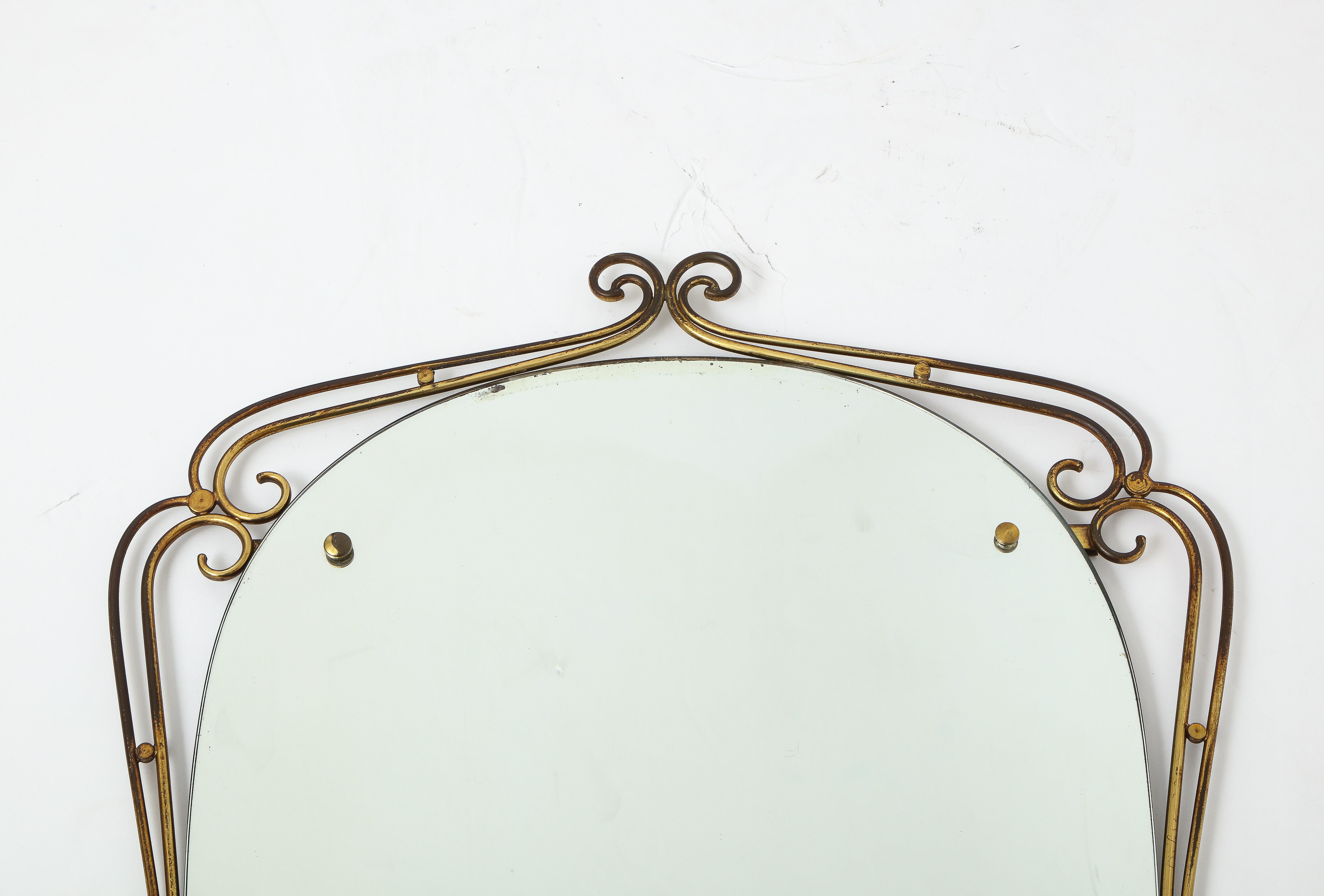 An Italian 1950's oval shaped brass mirror with exuberant and whimsical scroll motif. 
Italy, circa 1950 
Size: 39