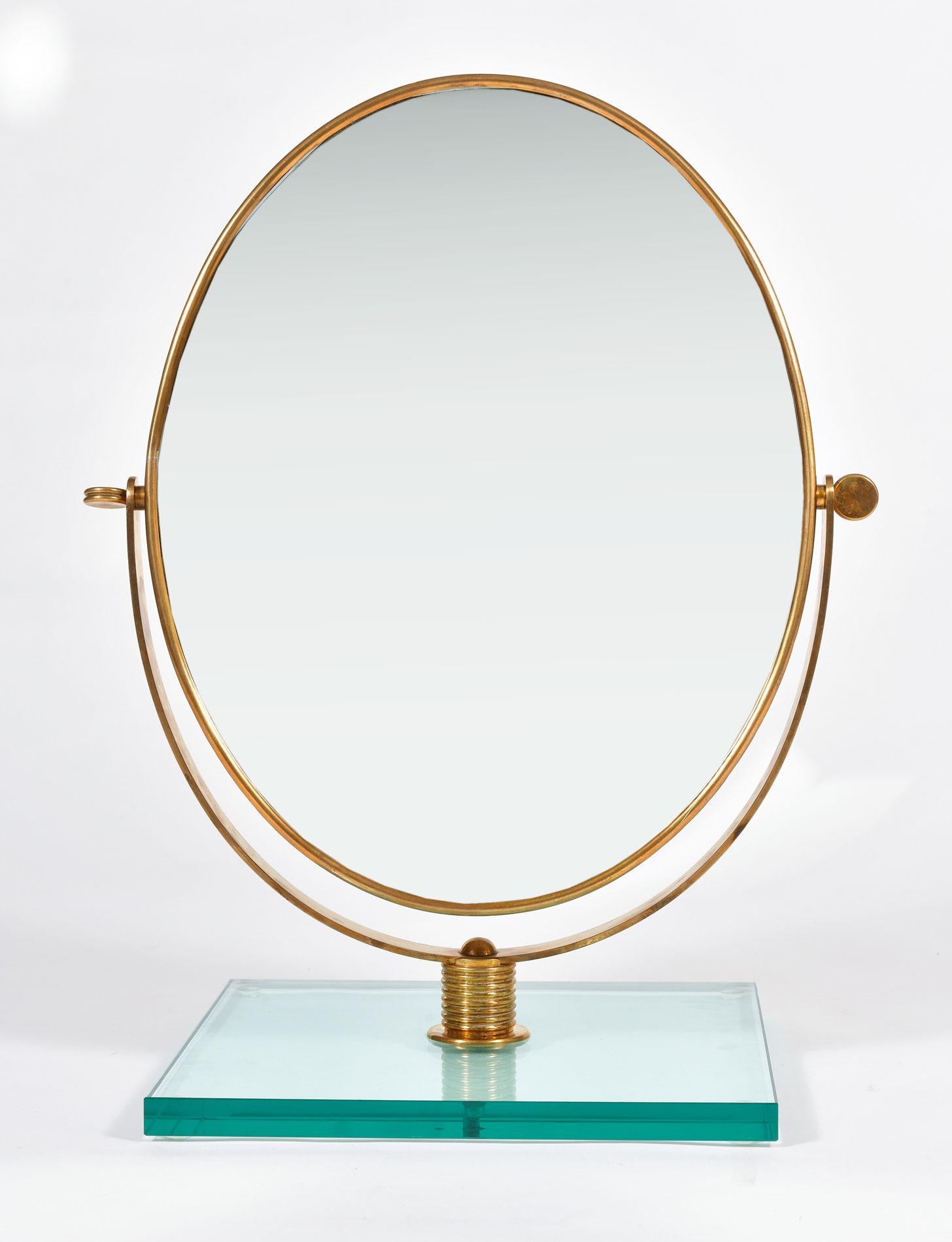 Chic brass framed table mirror angled within decorative brass support which allows the mirror to be re-positioned as required. Sits on thick square green glass base.