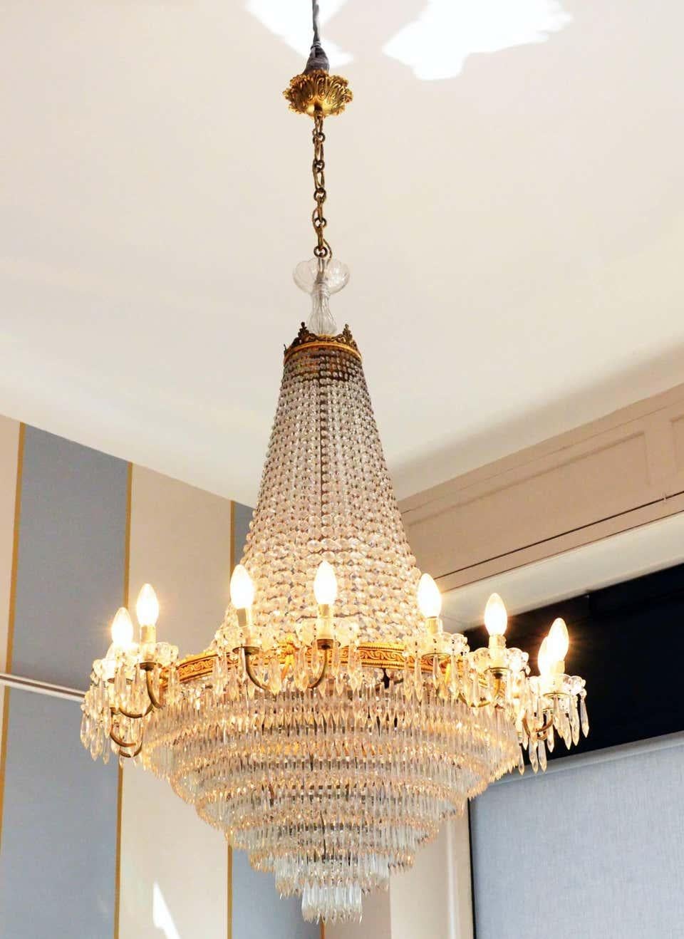 Chandelier Empire style, crystal drops and golden brass details

A crystal drops chandelier, Italy midcentury 1950s period. Golden brass detail and rings. The chandelier comes with 32-light, 16 inside and 16 outside. Newly rewired. It measures: