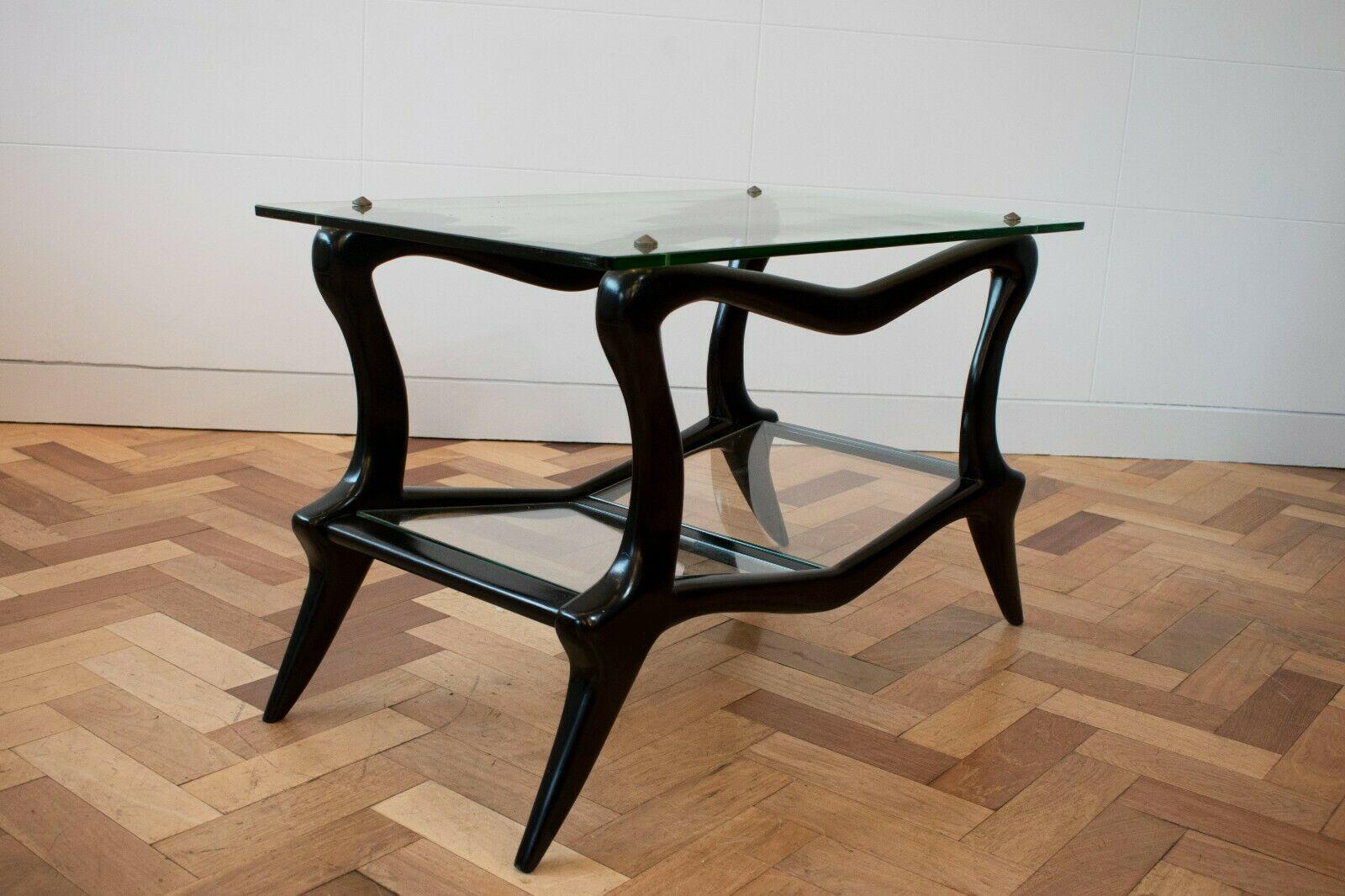 An amazing and rare Italian 1950s glass coffee table with sculptural ebonised wood legs. 

This beautiful coffee table features a curved ebonised wood form that holds a glass top. 

A sculptural piece that encapsulates the beauty of Mid-Century