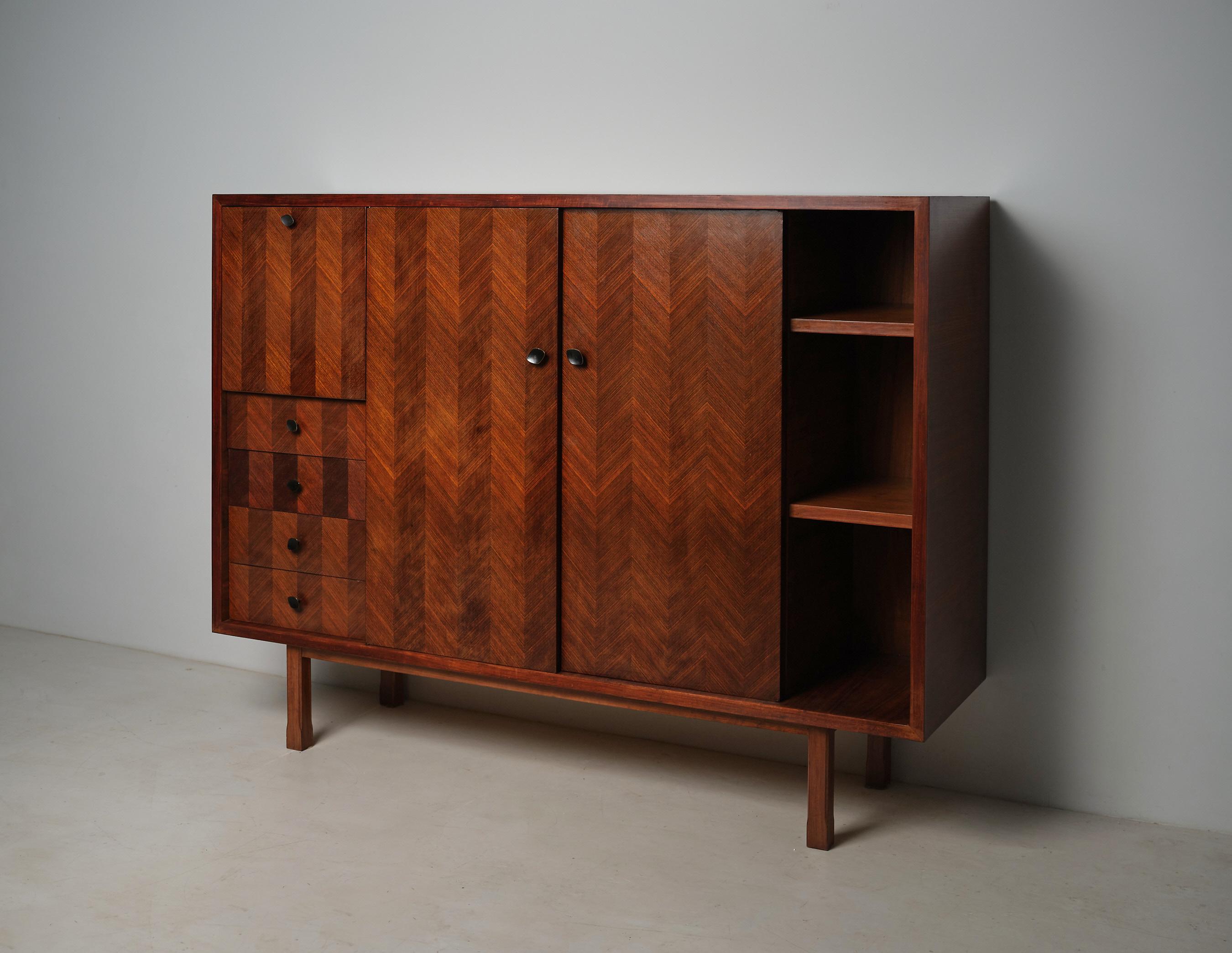 This Italian high cabinet from the 1950s reflects mid-century design with a structured, elegant form. Crafted from exotic wood with a chevron veneer pattern on the front panels, it showcases the refined aesthetics typical of Italian craftsmanship