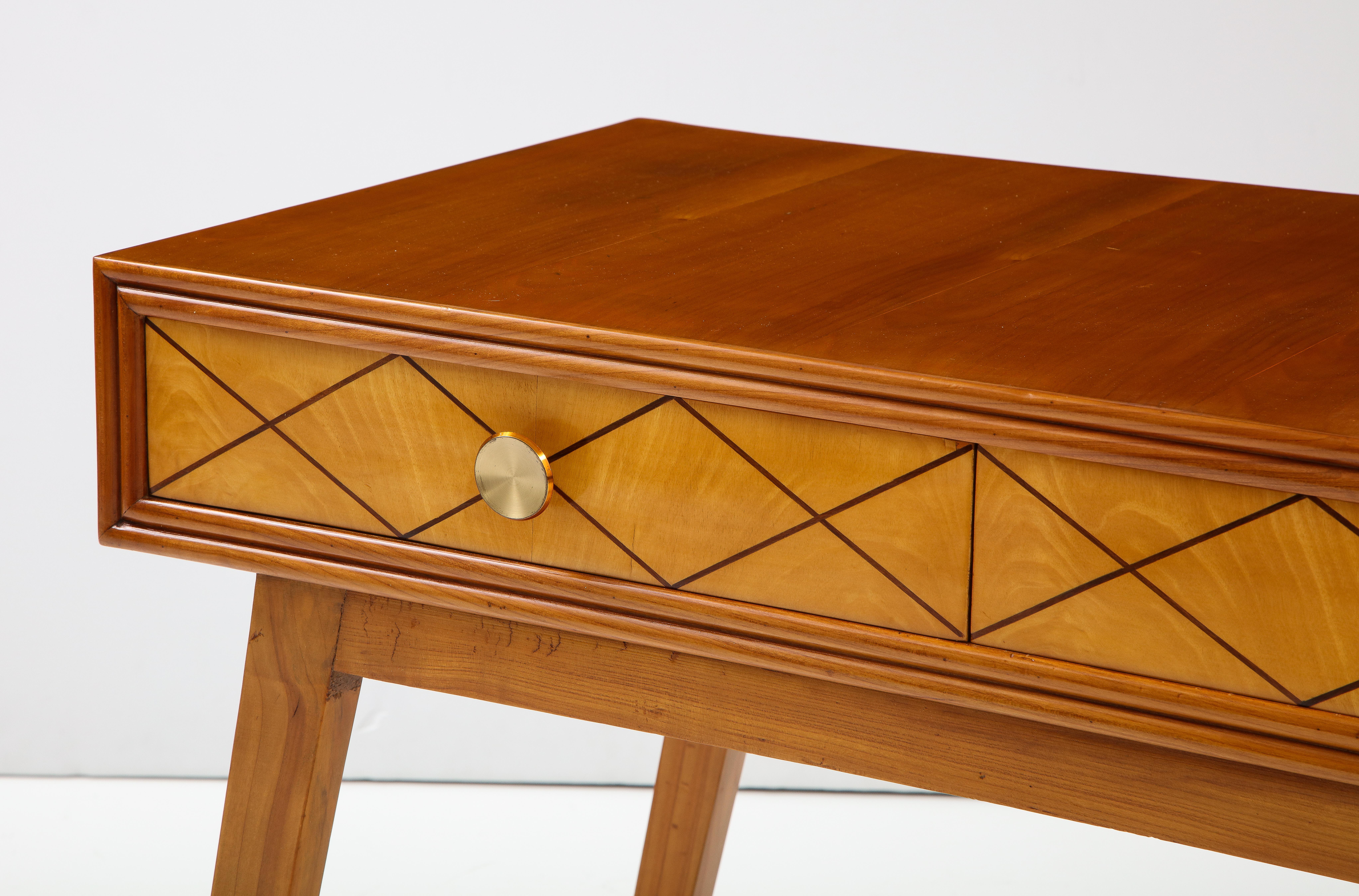 An elegant Italian 1950's maple wood desk; the rectangular apron inlaid in walnut geometric motif and with two drawers, opened with sleek circular brass handles. The whole supported on canted tapered legs. Can be used as a desk, vanity or table;