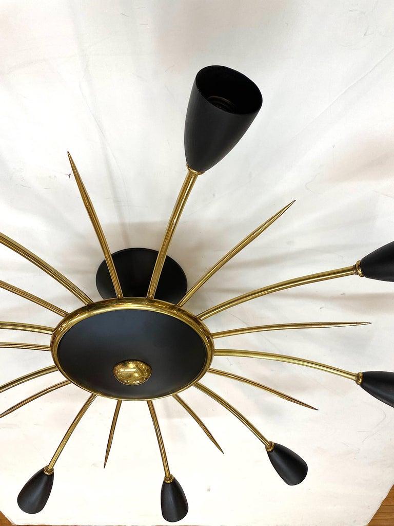 A spectacular and large 1950s Italian brass and black enamel light fixture in a star-burst design. The light measures 31.5 inches in diameter and is a direct to ceiling mount. The drop is about 10 inches There is a main central dish from which 9