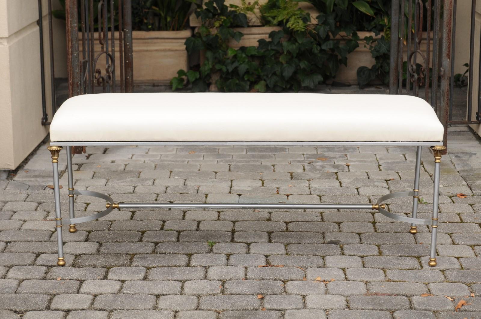An Italian vintage Maison Jansen style steel and brass backless bench from the mid-20th century, with floriform capitals and new upholstery.  This Italian Mid-Century Modern Maison Jansen style backless bench features a rectangular upholstered seat