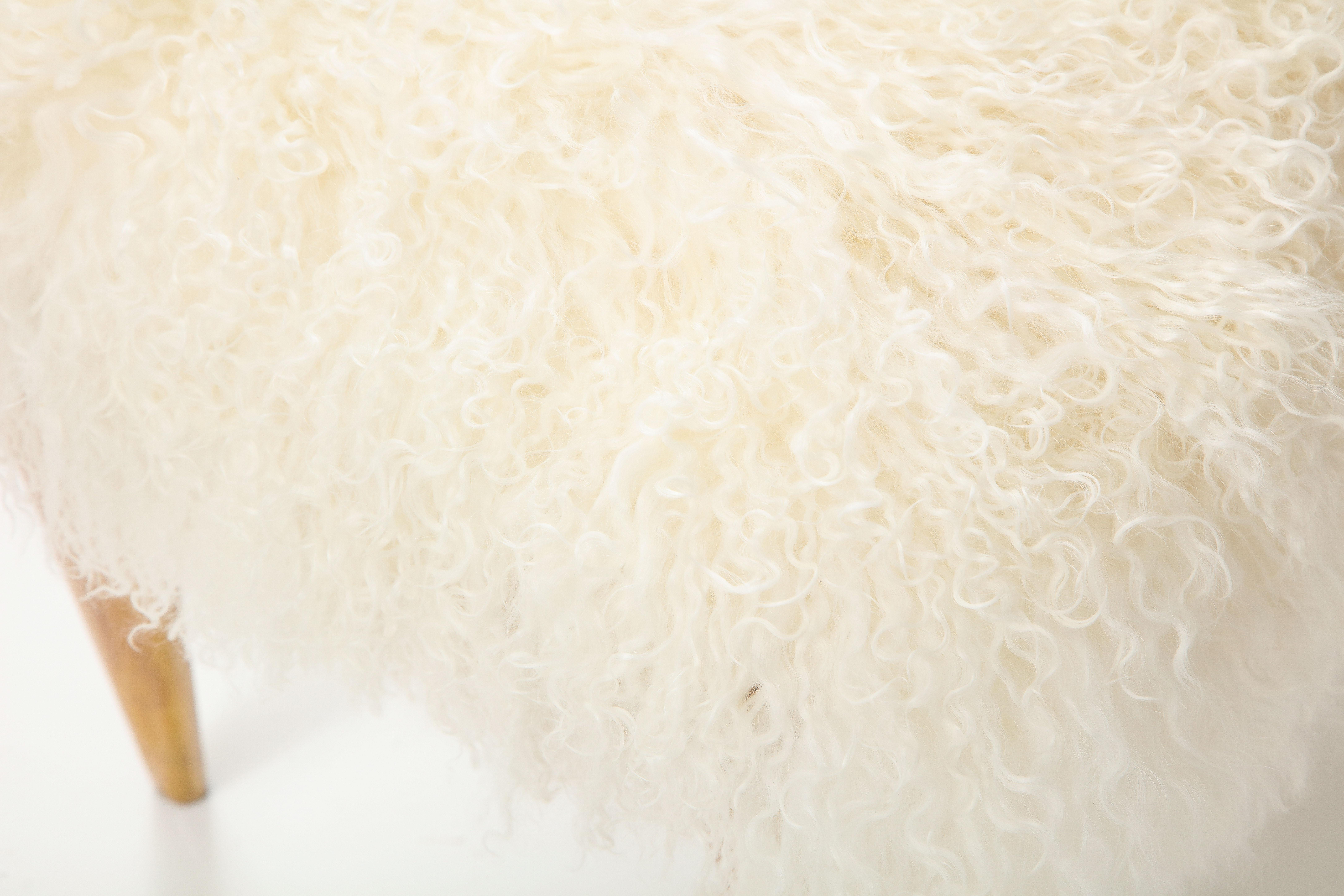 Ein elegant ausgestatteter italienischer Hocker oder eine Bank aus Ahornholz der 1950er Jahre mit anmutig verjüngten und angewinkelten Beinen; die Platte ist neu mit einem luxuriösen cremefarbenen/weißen langhaarigen mongolischen Schaffell