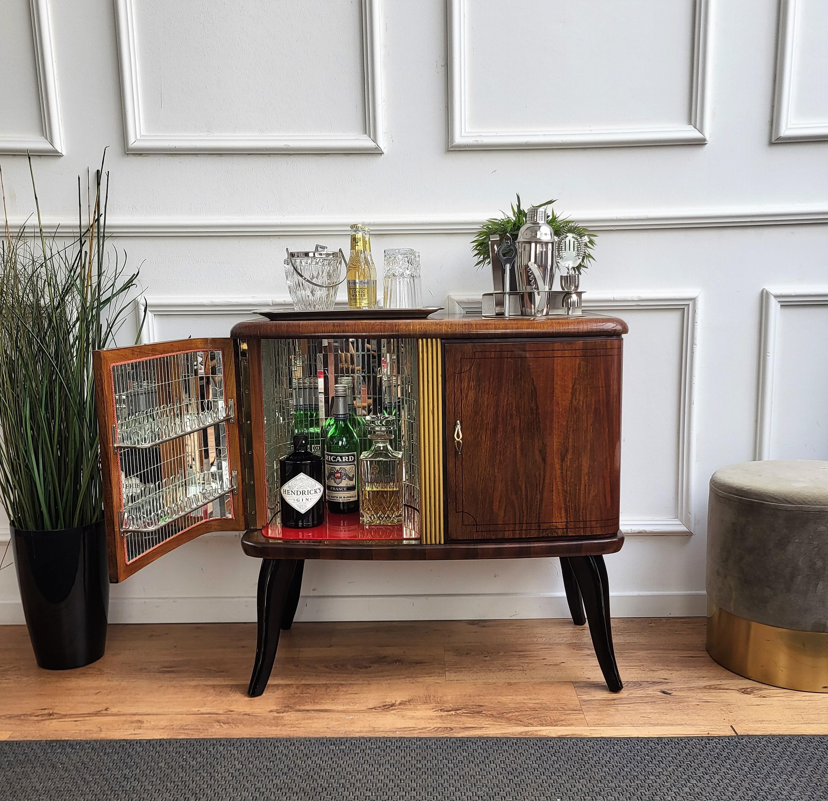 Very elegant Italian Mid-Century Modern drinks dry bar cabinet with beautiful wood, two doors and great brass linear decors and handles. When opened, on the left side an amazing interior part in mirrors mosaic and glass shelf ideal as server or