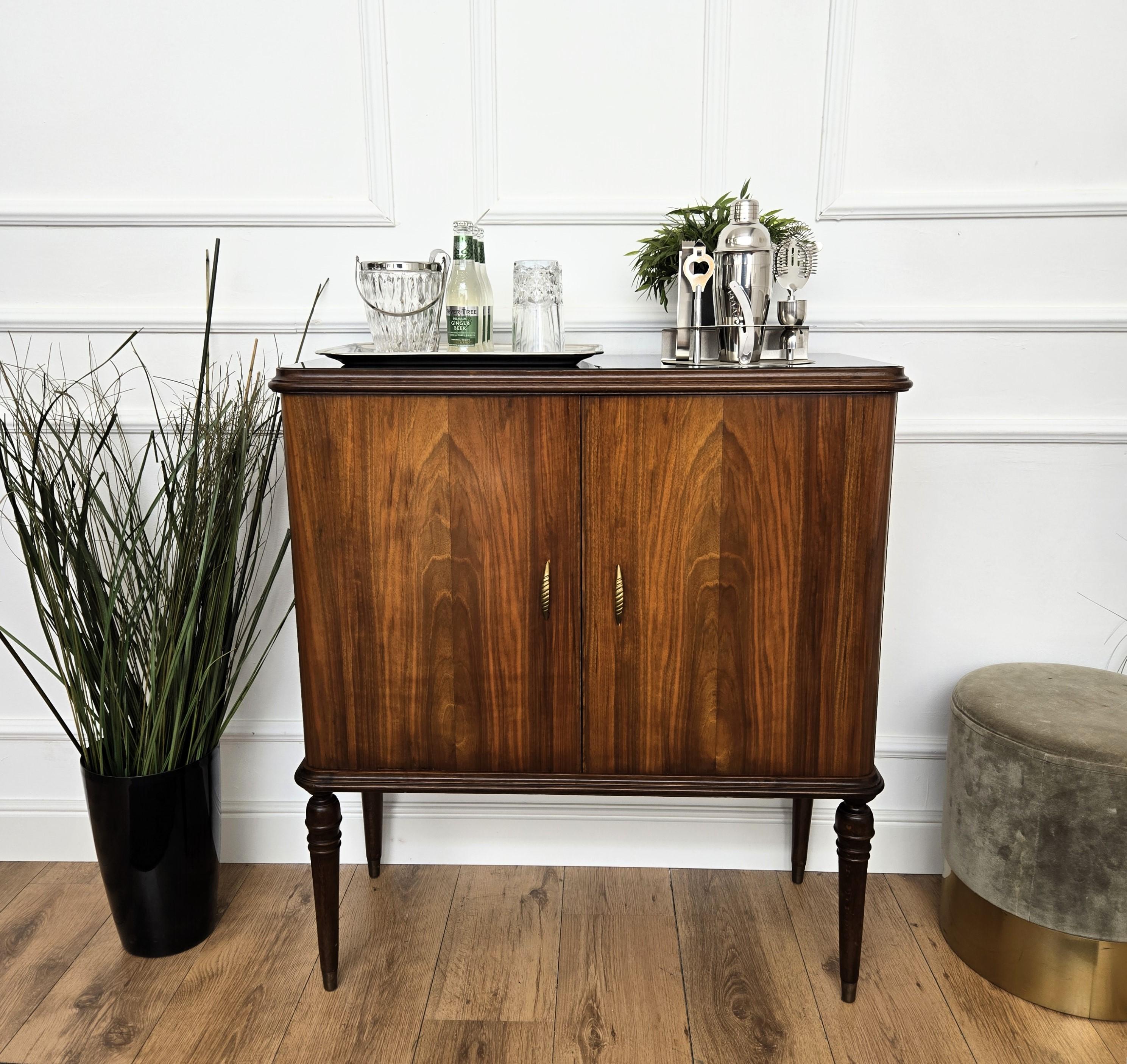 Very elegant Italian Mid-Century Modern drinks dry bar cabinet with beautiful wood, two doors, framed black glass top and brass details as the handles. When opened, on the right side an amazing interior part in mirrors mosaic and glass shelf ideal