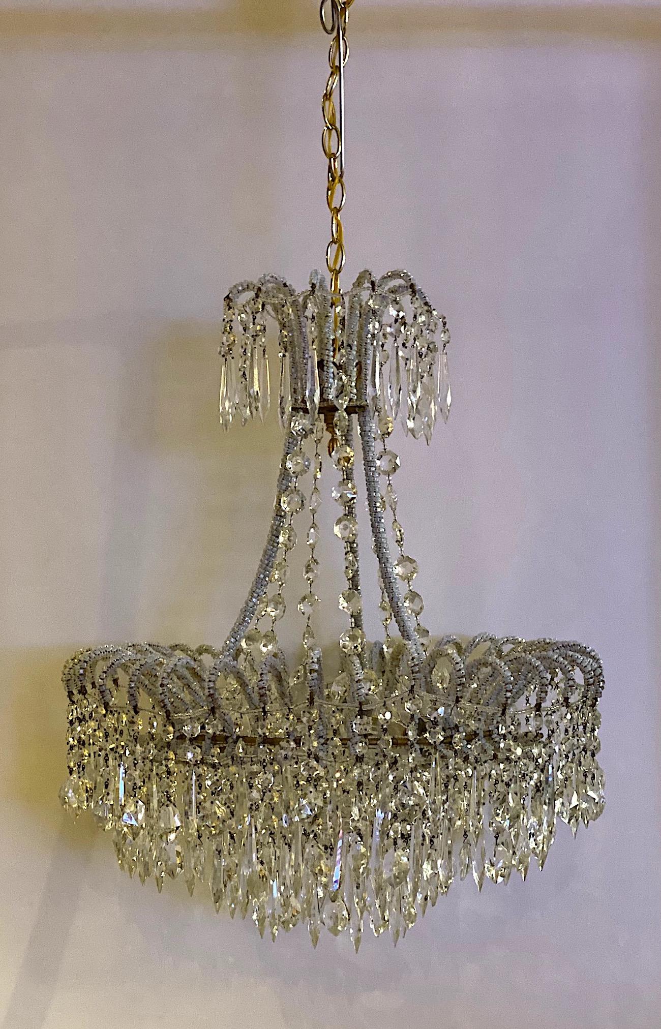A truly charming and elegant Italian made 1950s Hollywood Regency style chandelier. The body of the chandelier is 21 inches in diameter and 25 inched tall. The three main iron supports attaché to a large ring on the bottom and a smaller one on top.