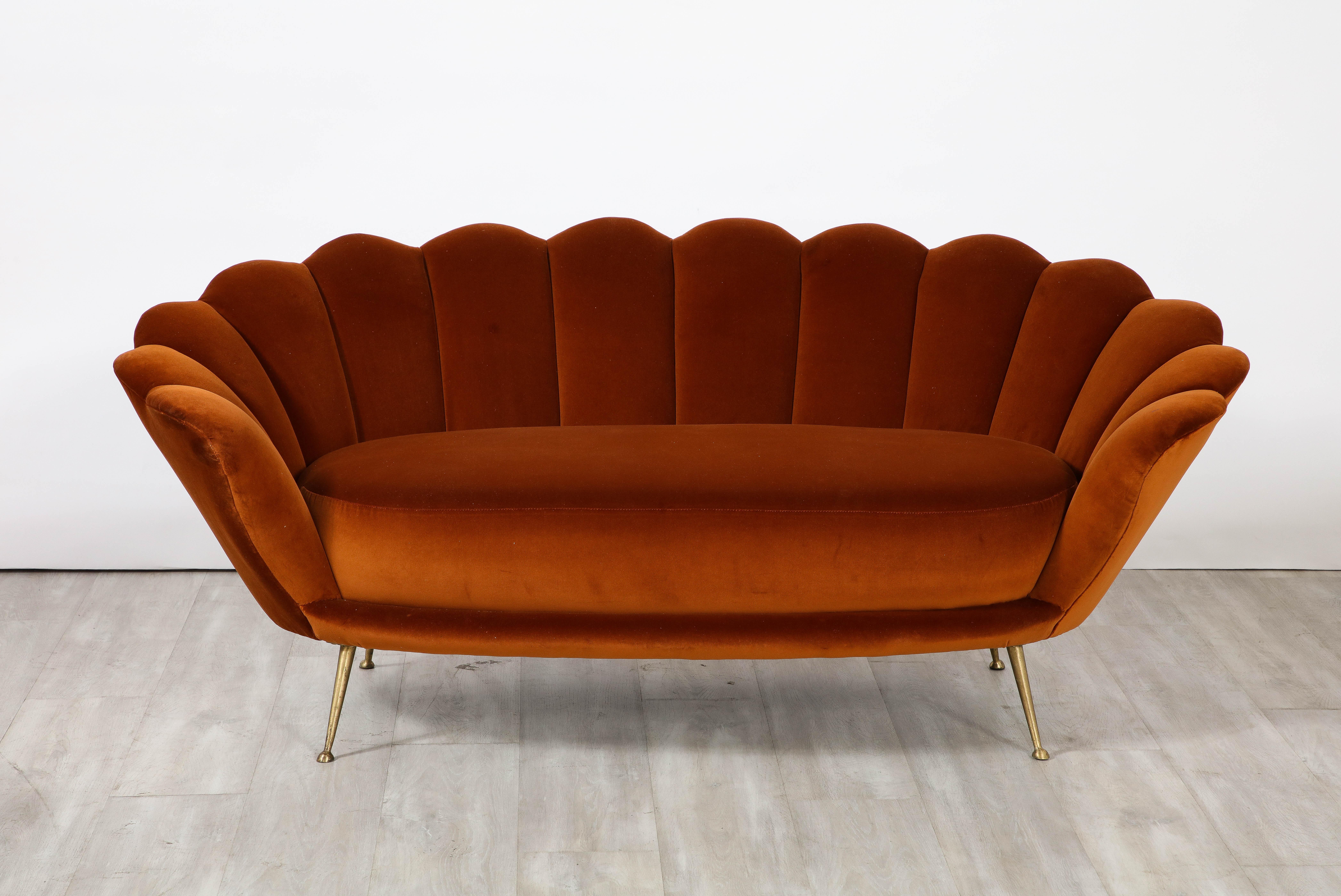 A decadently designed Italian 1950's settee with a scalloped or petal shaped form and luxuriously upholstered channeled back tufting. The settee has been fully restored and newly reupholstered in a rich apricot colored cotton European velvet. The