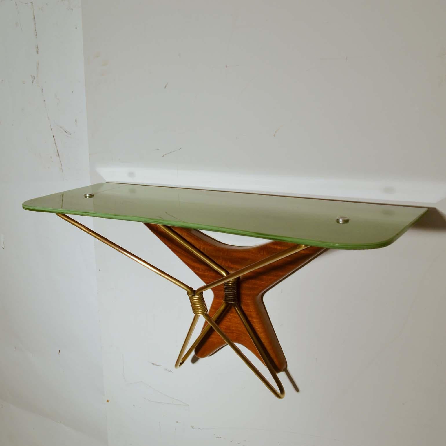 Wall mounted console table is made of sage green hand colored glass resting on top of a brass polished star shaped frame which is attached to a hand carved mahogany back rest that follows the shape of the brass frame. 
Ideal console for a small