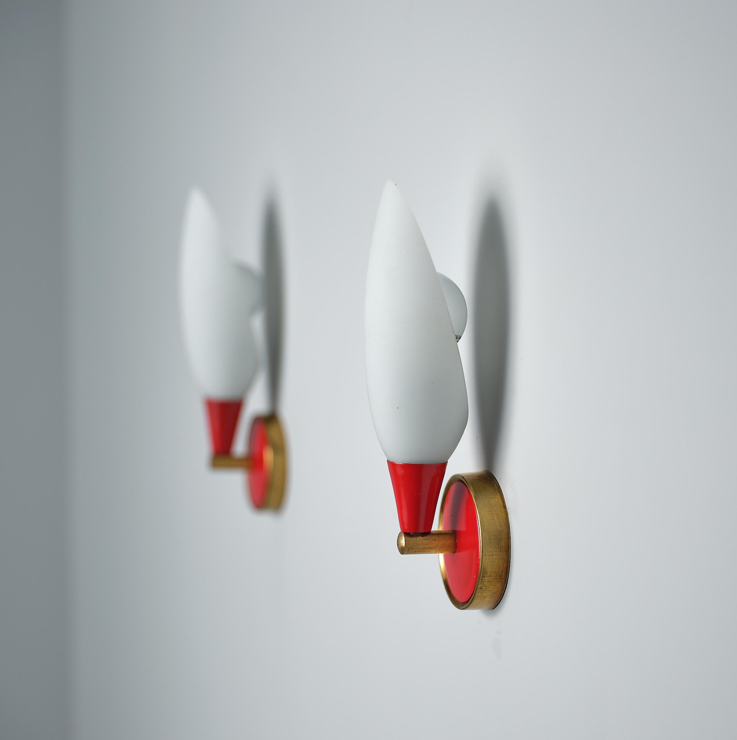 This pair of appliqués embodies the timeless elegance of Italian design from the 1950s. Crafted with precision in red lacquered metal and brass, these fixtures showcase a sleek modern style that seamlessly merges with classic aesthetics. The opaline