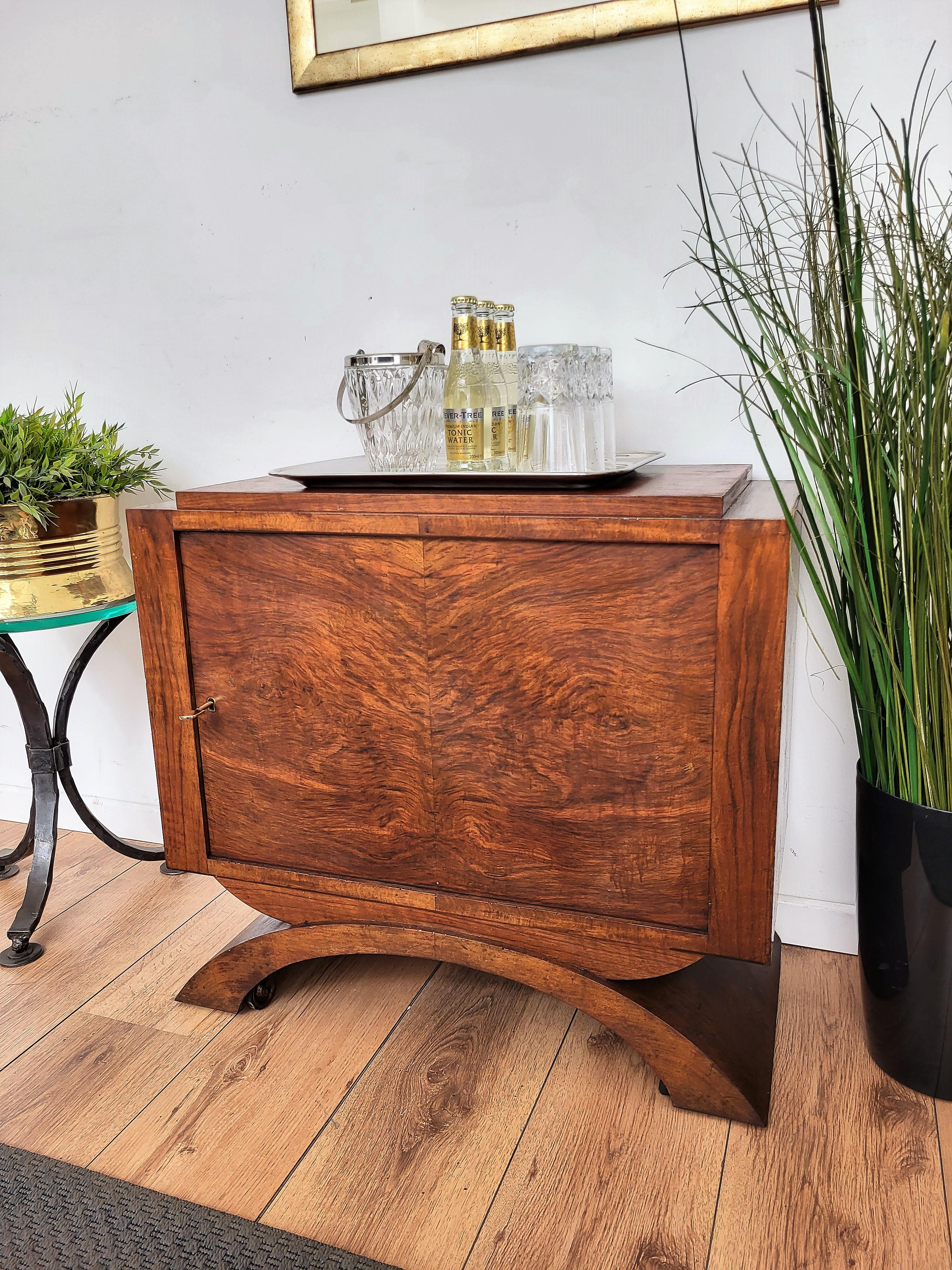 Very elegant Italian Mid-Century Modern drinks dry bar cabinet in beautiful veneer walnut wood and central turning door with brass key. When turned and opened we have two glass shelves with metal frame and bottle holder plus 2 hidden bottles holders