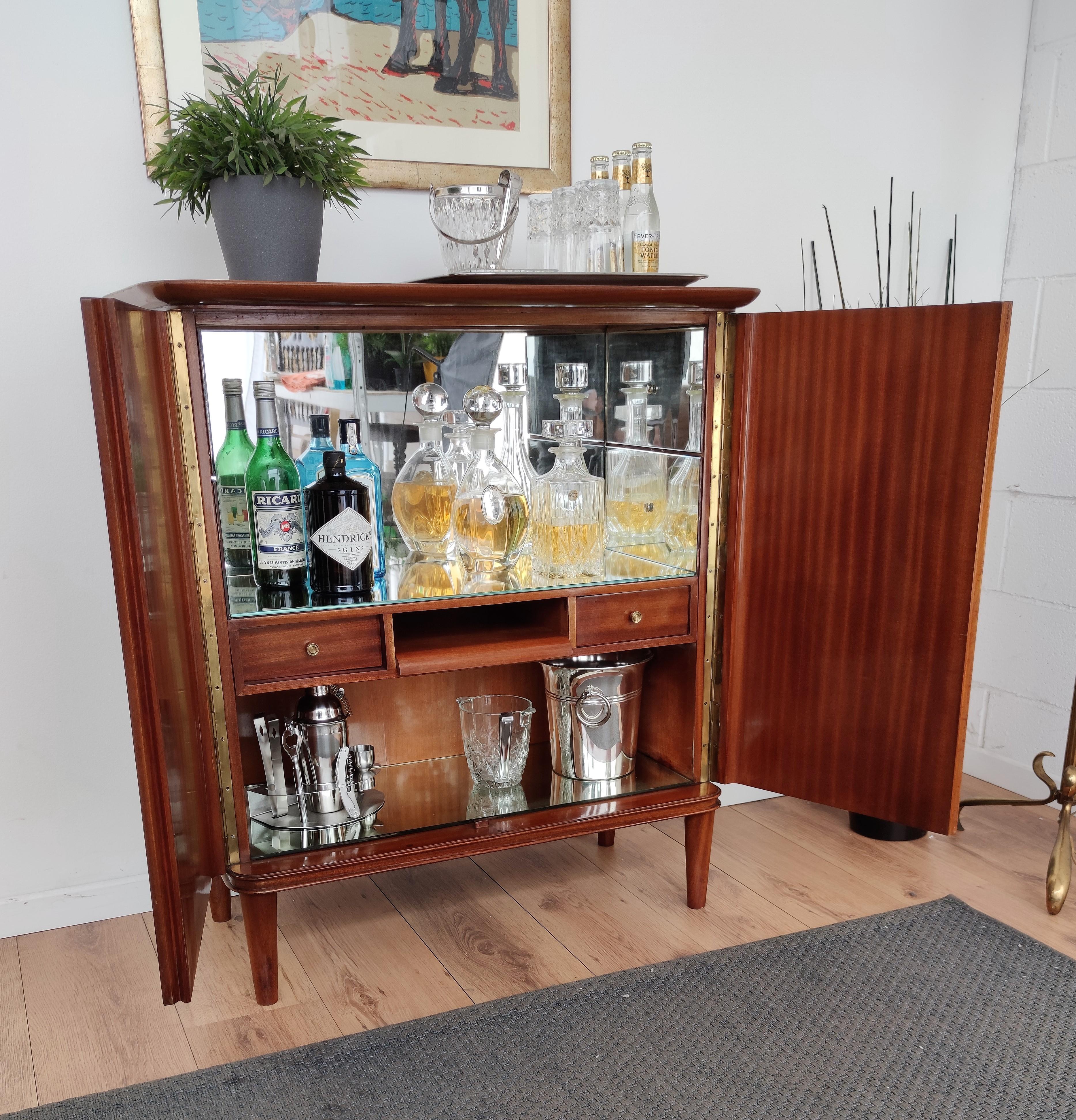 Beautiful and very elegant Italian Art Deco Mid-Century Modern dry bar cabinet, in greatly worked and inlay decorated veneer walnut wood on the double front doors with brass details as for the locking key. The interior part is a classic dry bar