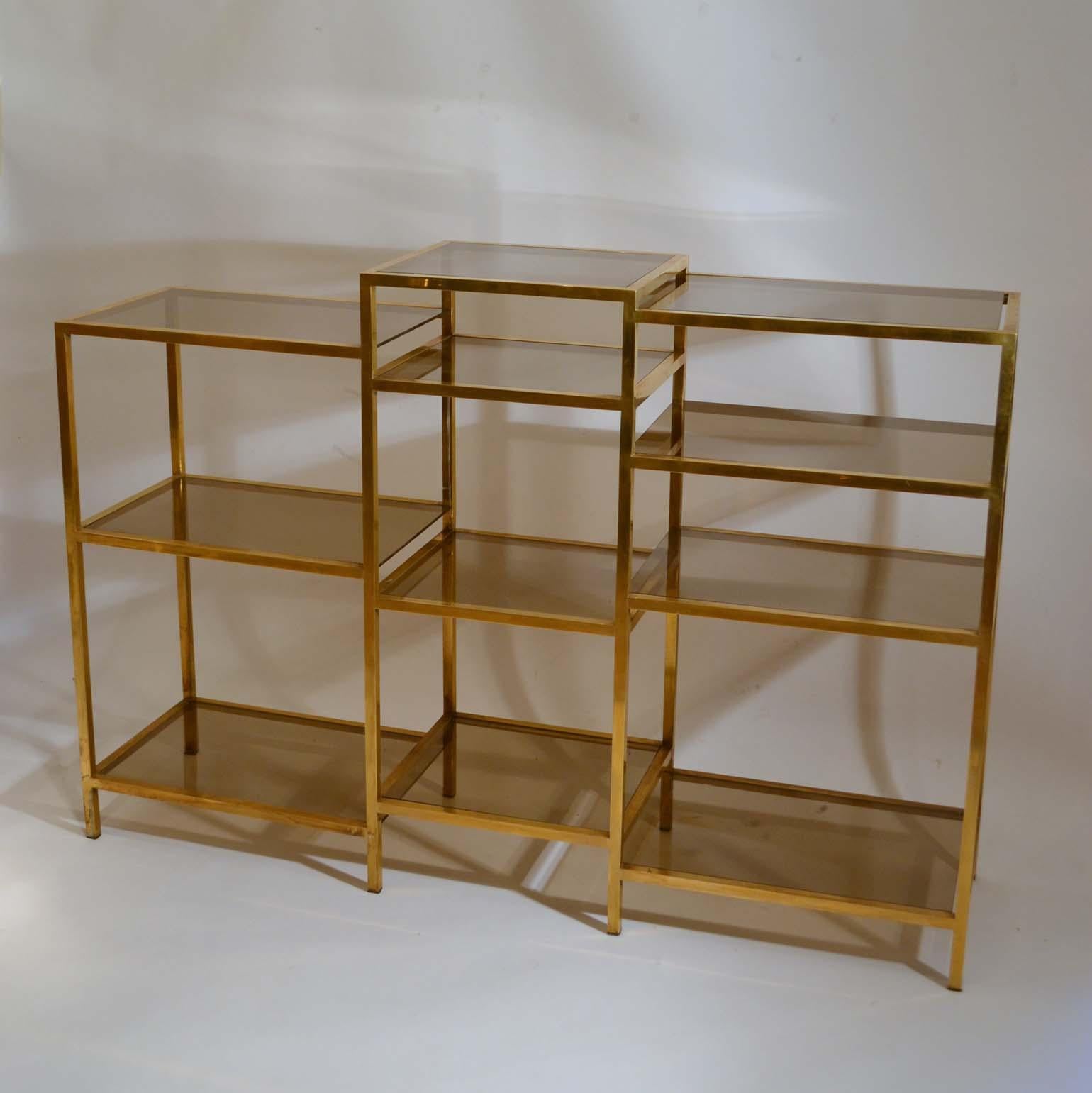 Freestanding multi-leveled brass étagère is divided in three sections of 3 to 4 shelves each at different levels, which varies from (96-106 to 108.5cm) with lightly tinted glass insets. Produced in the 1970s, the Italian company Romeo Rega started