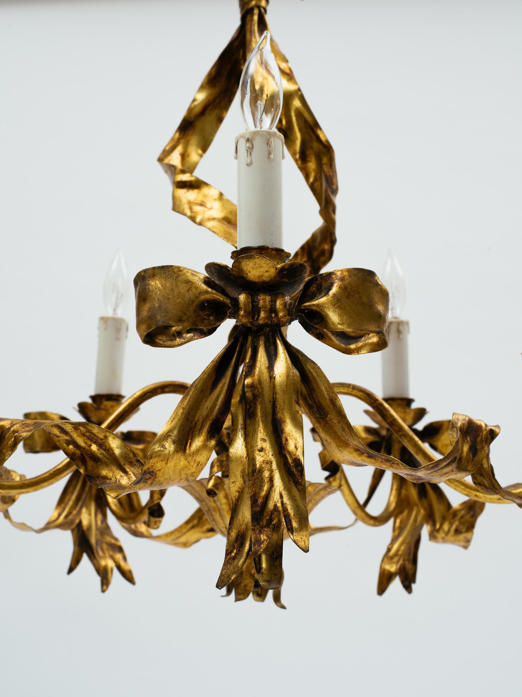 Italian 1960s gilt tole ribbon chandelier with six candle lights and fluted gilt tole ceiling cap. Chandelier bulb socket size.