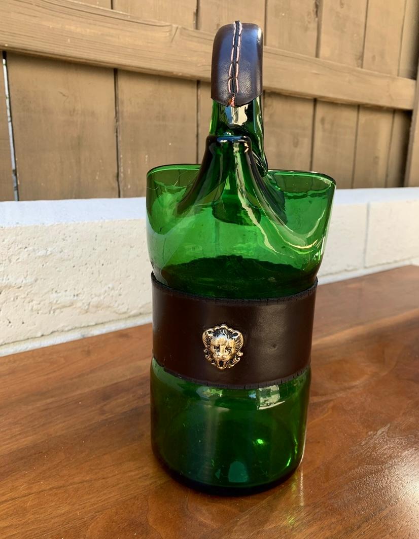 Stunning 1960s Italian mouth-blown glass pitcher. Perfect for barware use and to serve lemonade or water, this lovely green glass pitcher is accented with a dark brown handstitched leather handle. Hand stitched leather wrap around the base of the