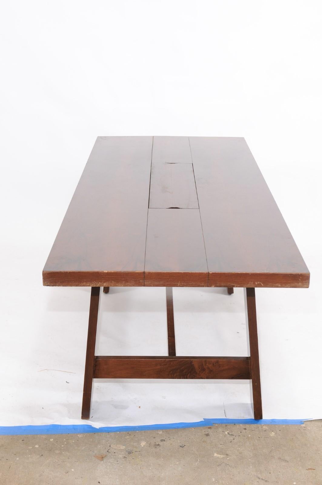 An Italian walnut veneer dining table designed by Silvio Coppola for Bernini in the 1960s. Born during the midcentury period, this handsome Italian walnut veneer dining table features a rectangular planked top with removable tray in the center,