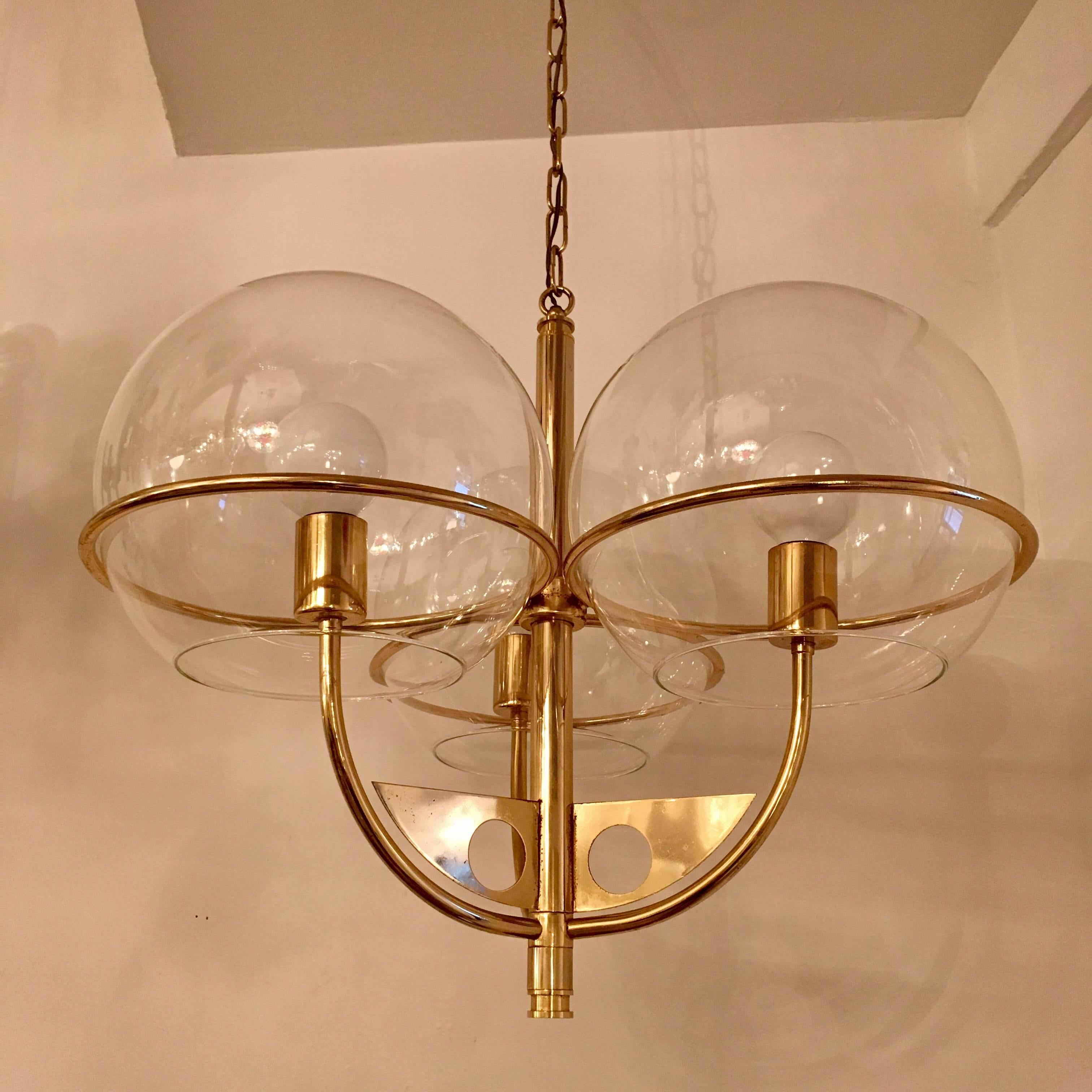A 1970s swooping golden brass Italian chandelier with three large glass globe shades. Newly rewired. Body is 21” High . 