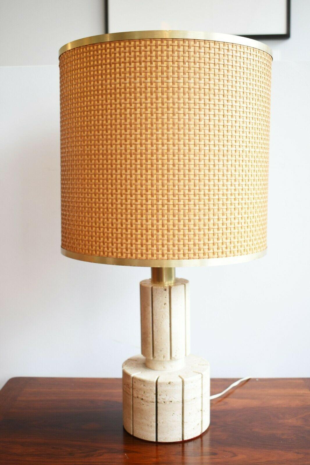 An Italian 1970's mid 20th century modern desk / table lamp featuring a woven cylindrical bamboo shade with an elegant brass taped top and bottom. 

The lamp has a cylindrical travertine base, detailed with deep vertical grooves, connecting to