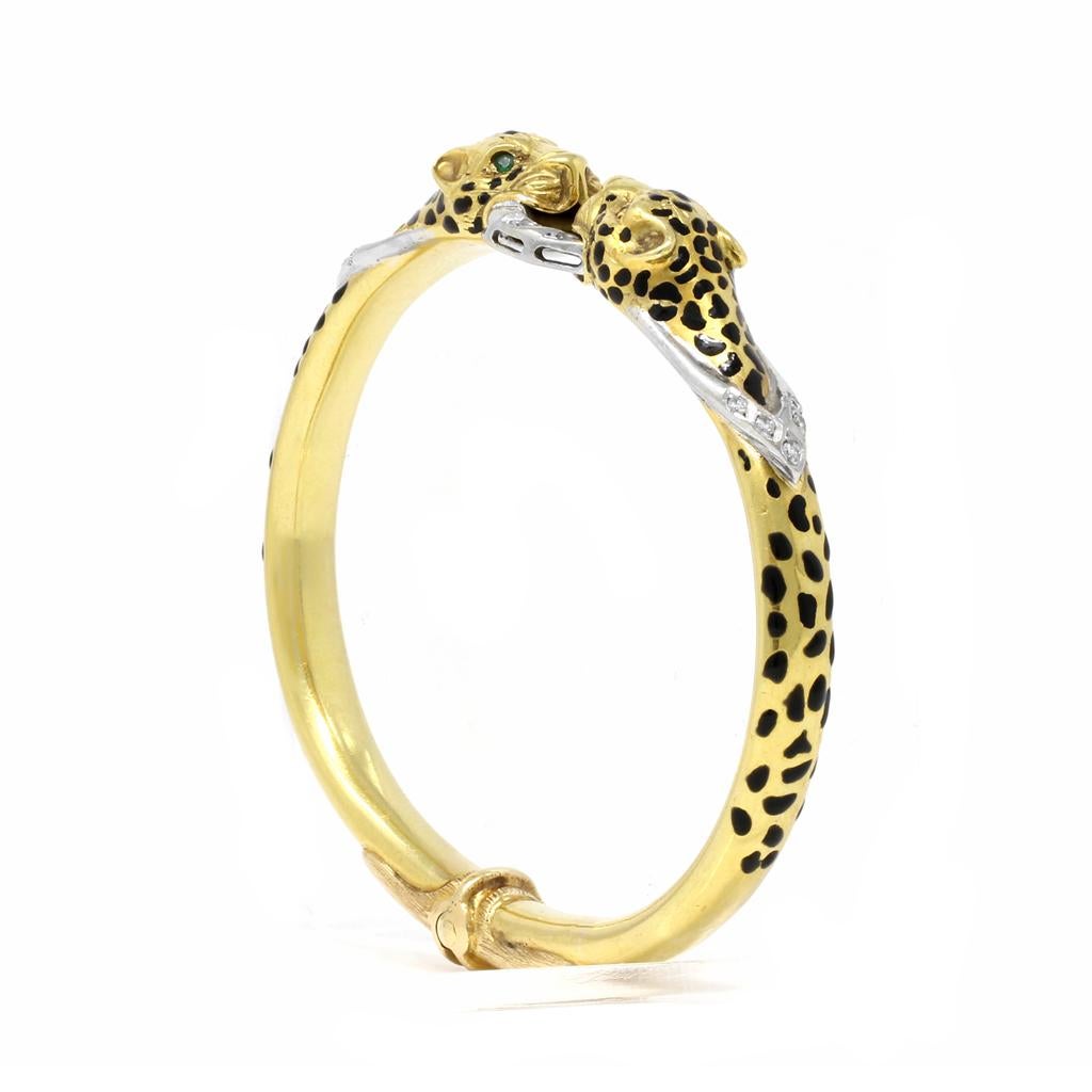 An Italian cheetah enameled pattern Diamond and Emerald bangle bracelet in 18K yellow gold, size 7.5. Made in Italy during the 1970s, this exquisite bangle features two cheetahs with Emerald eyes, biting a central ring. Accented with Diamonds of