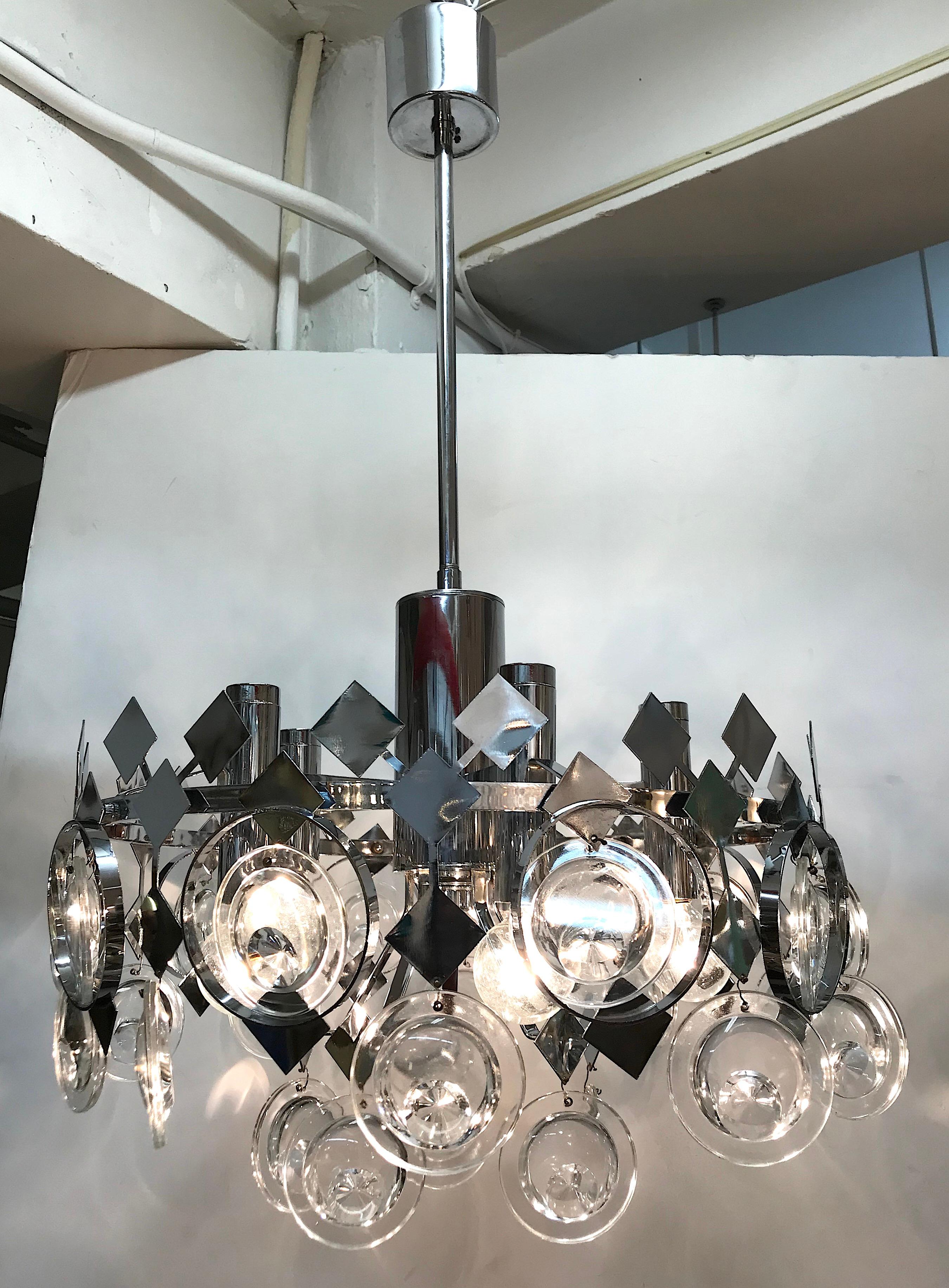 A fabulous and unique 1970s Italian chrome chandelier with optical glass lens disks. Light and airy in design, the body of the chandelier is very open. It consists of diamond pieces mounted onto a circular frame interspersed with glass disks. Each