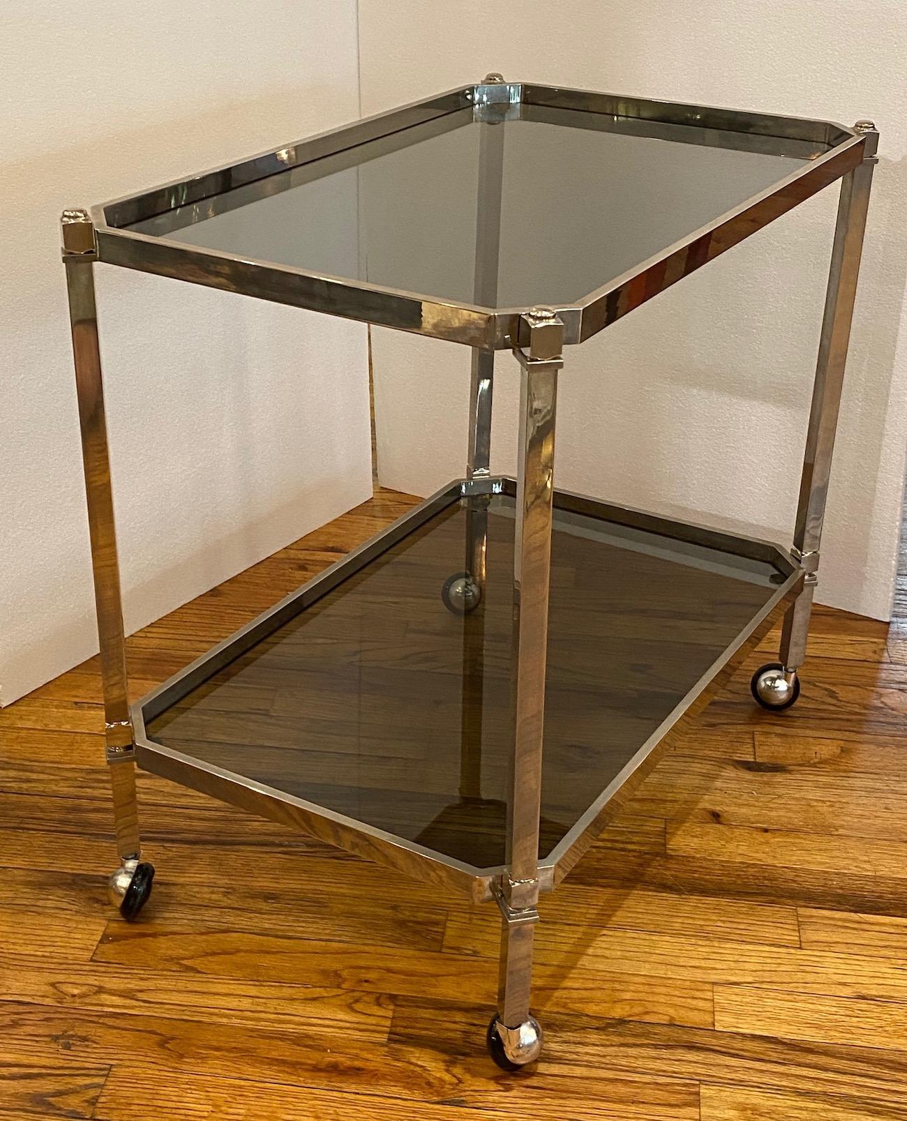 Made and purchased in Italy is this 1970s chrome with smoke grey glass two tier bar or serving cart. Rectangular in shape with cut corners. The grey glass panels fit perfectly into the cart frame. Black rubber wheels in chrome dome casters. Cart