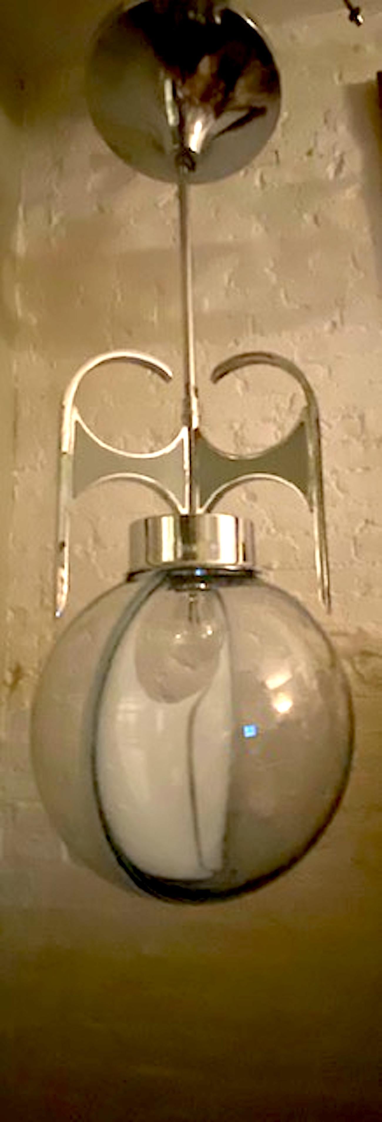 A wonderfully sculptural Italian pendant light from the 1970s in the style of the Italian lighting company Vistosi. The hand blown glass shade is clear with a light blue/grey tint. It has a decorative white glass crescent shape piece in the middle.