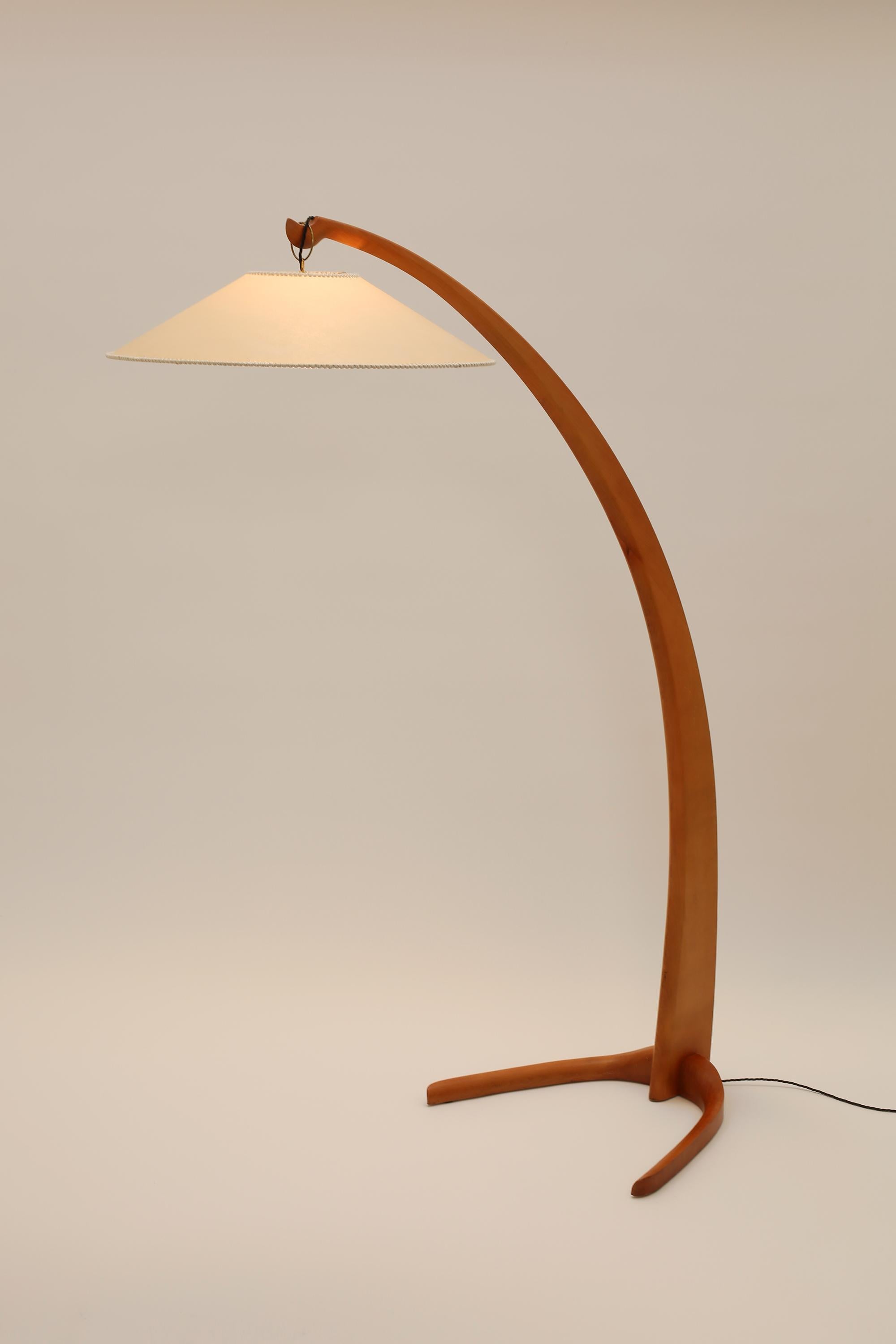 A statement floor lamp in curved beech with two prong base and original, string-bound parchment coolie shade. After a 1940s design, Italian, c. 1970s.