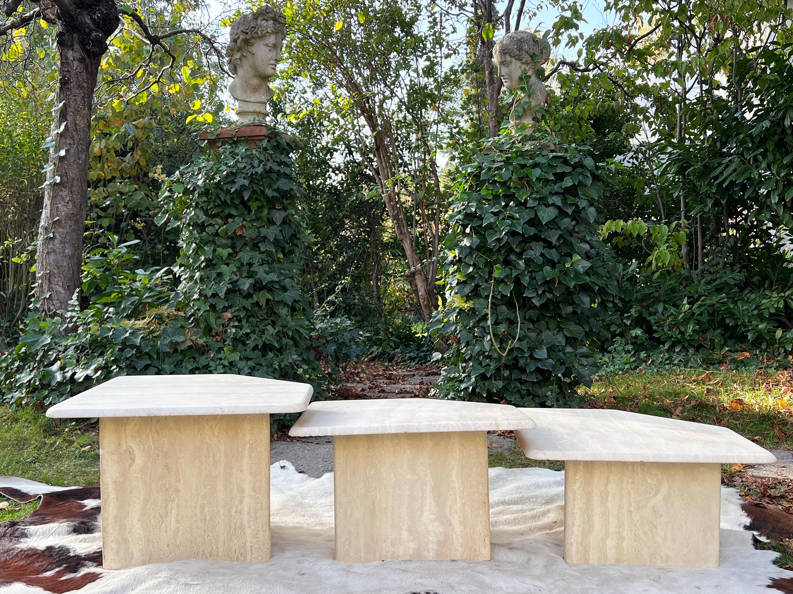 Set of three nesting tables made of Travertine. Each table sits on a T shape base. The marble tops are a very cool shape! Beautiful travertine quality in very good vintage condition.  We love the beautiful tecture and decorative impact of this set.