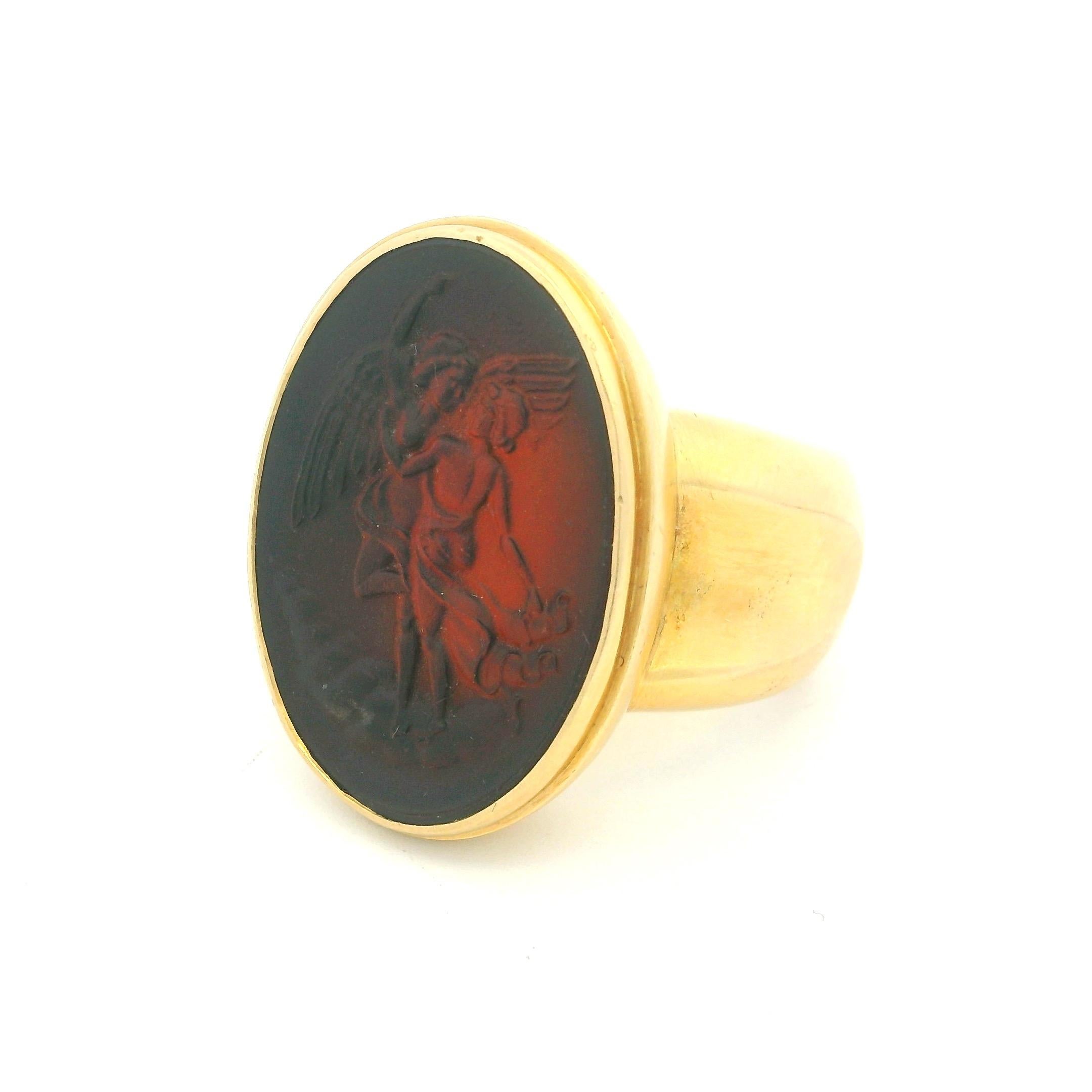 Remarquable bague de chevalière en intaille de style néo-étrusque italien, réalisée en or jaune 18 carats massif et pesant un poids impressionnant de 22,60 grammes. La pièce maîtresse est une intaille ovale en cornaline, finement sculptée de deux