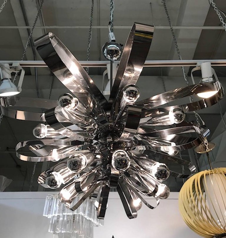 An absolute show stopper and statement piece is this large Italian chrome chandelier in the form of a flower. Two and half inch wide bands of chromed metal zig zag from larger to smaller from top to bottom to create 24 open petals. In-between each