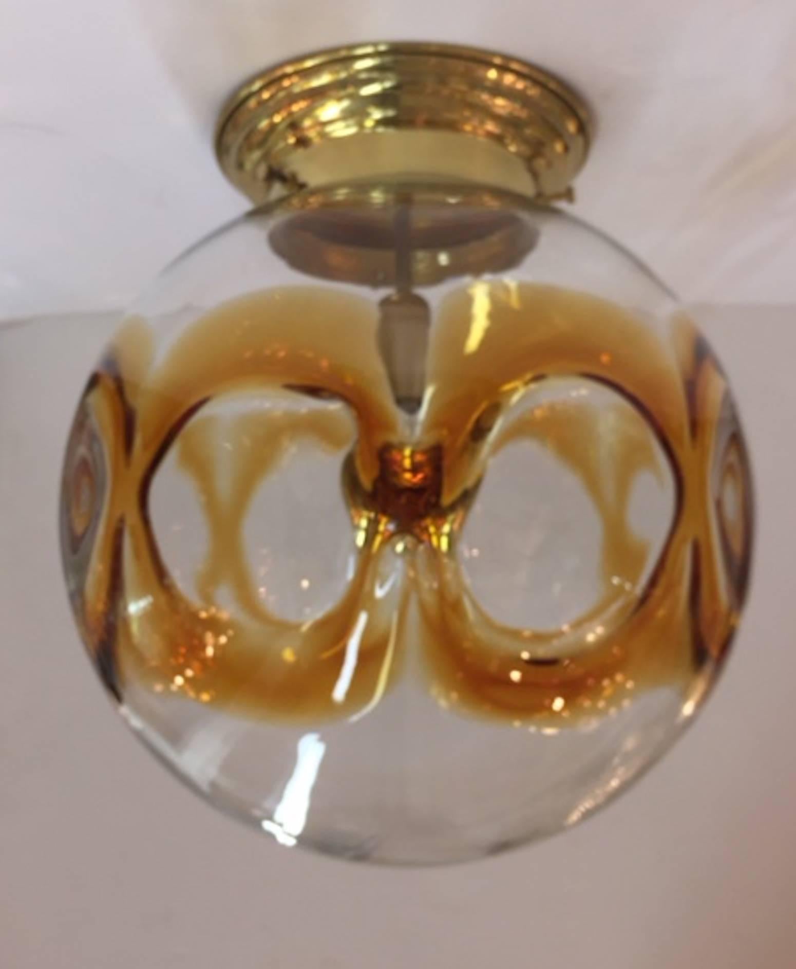 Italian 1970s ceiling mount light fixture. Large hand blown glass shade in clear with amber circular design. Made in Murano, Italy, circa 1970. Brass polished and lacquered. Rewired. Show with gold dome standard light bulb. Globe shade measures 13