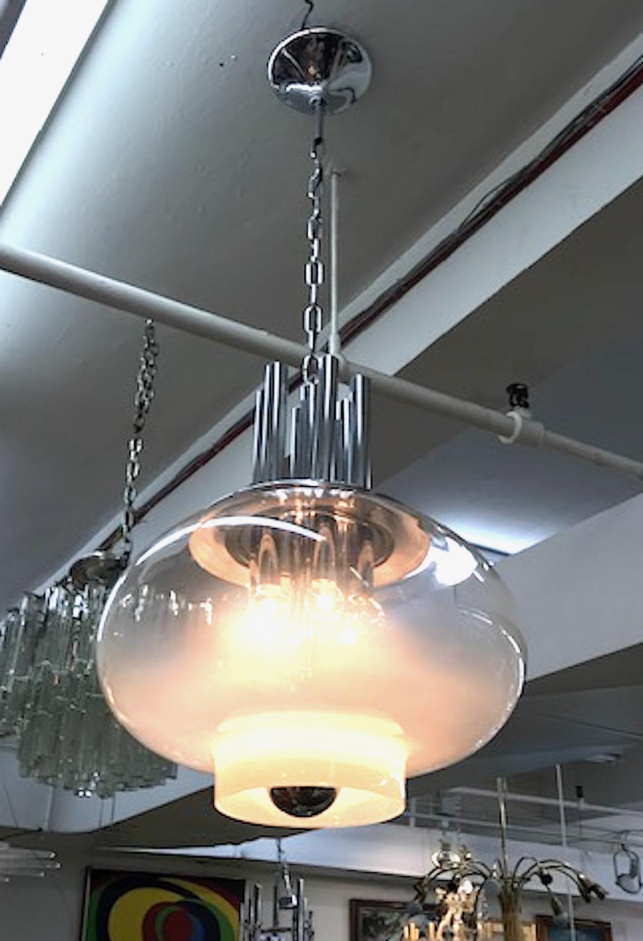 Large and sculptural Italian 1970s chrome and glass pendant light. A hand blown clear and white Murano glass shade houses six interior candelabra bulb lights and is suspended from a sculptural chromed top piece. A standard socket, shown here with a