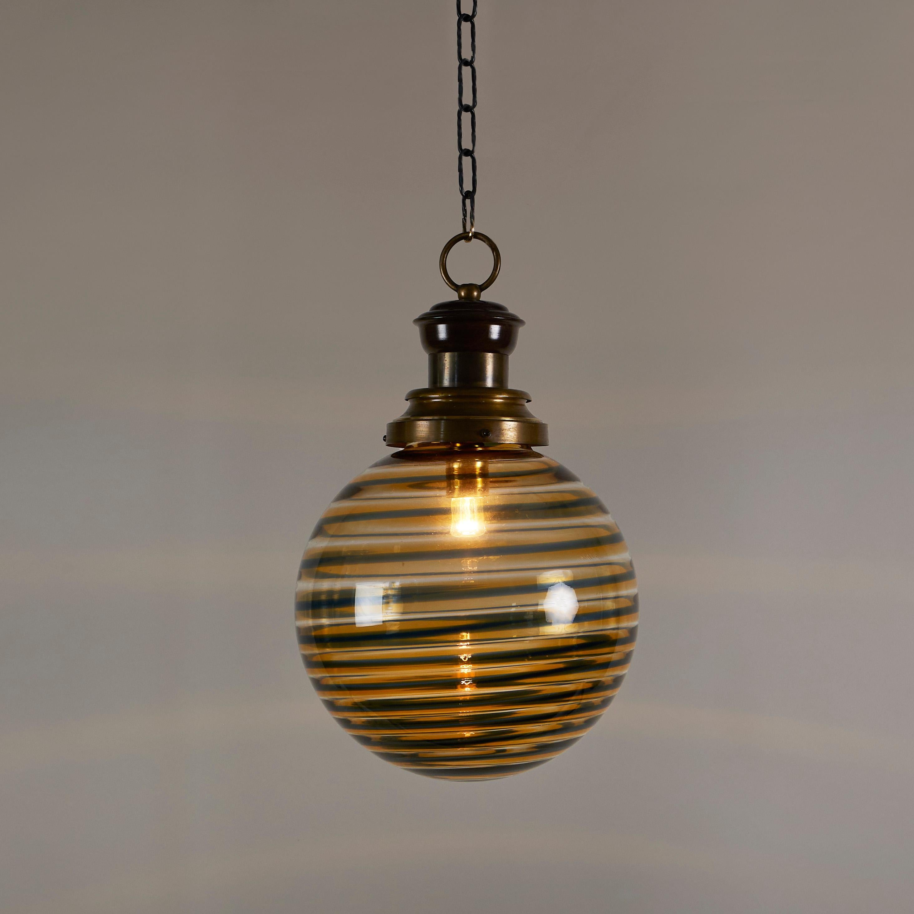 Murano handblown glass sphere pendant of pale amber glass with black swirl pattern. Brass fitting, chain and ceiling rose.
