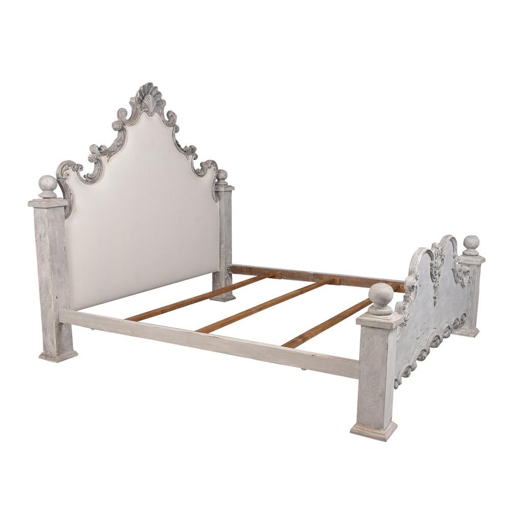 This Italian Baroque style King size bed frame features a wood frame painted a pale grey and oyster color combination with a distressed finish. There are detailed handcrafted carvings details all along the headboard and footboard. The boards have
