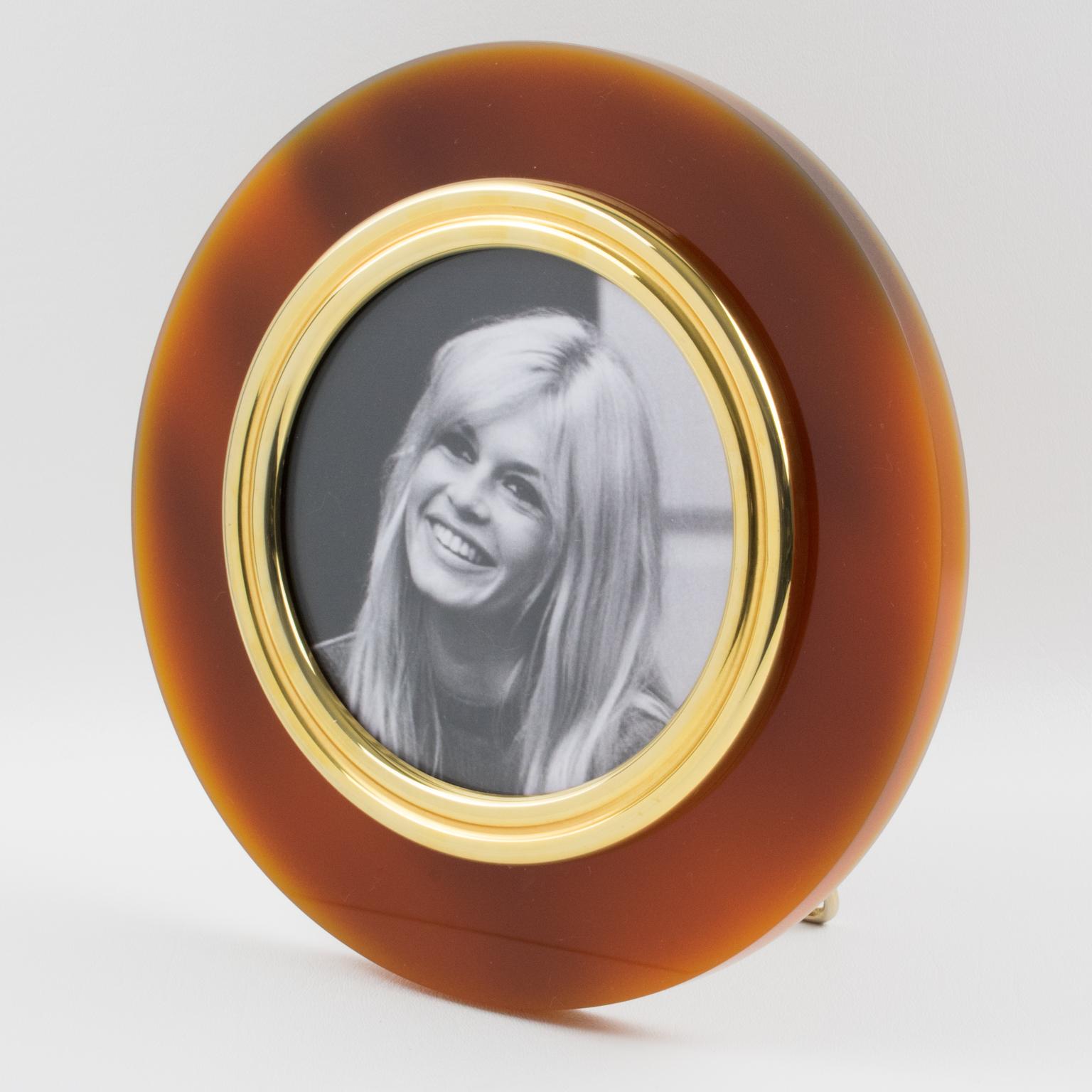 Stylish 1970s modernist round picture photo frame designed in the 1970s in Italy. Thick Lucite slab in red tea amber translucent color with gilt metal framing and easel. No visible maker's mark.
Measurements:
Overall: 9.07 in. diameter (23