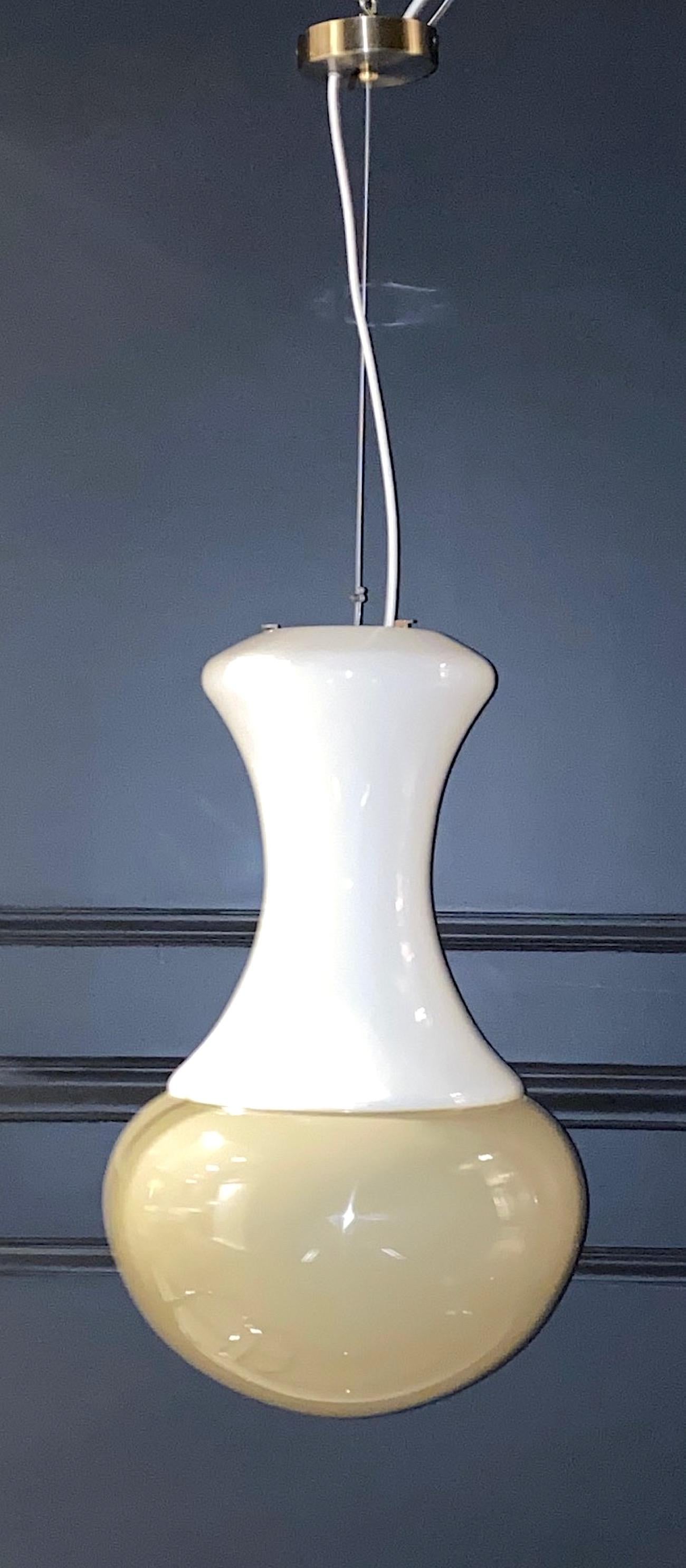 Une lampe pendante italienne au design épuré et élégant, vers 1970. Le pendentif est composé de deux pièces de verre soufflé à la main réalisées à Murano. Le haut est en verre blanc opaque et le bas est en verre opaque de couleur taupe/beige. Les