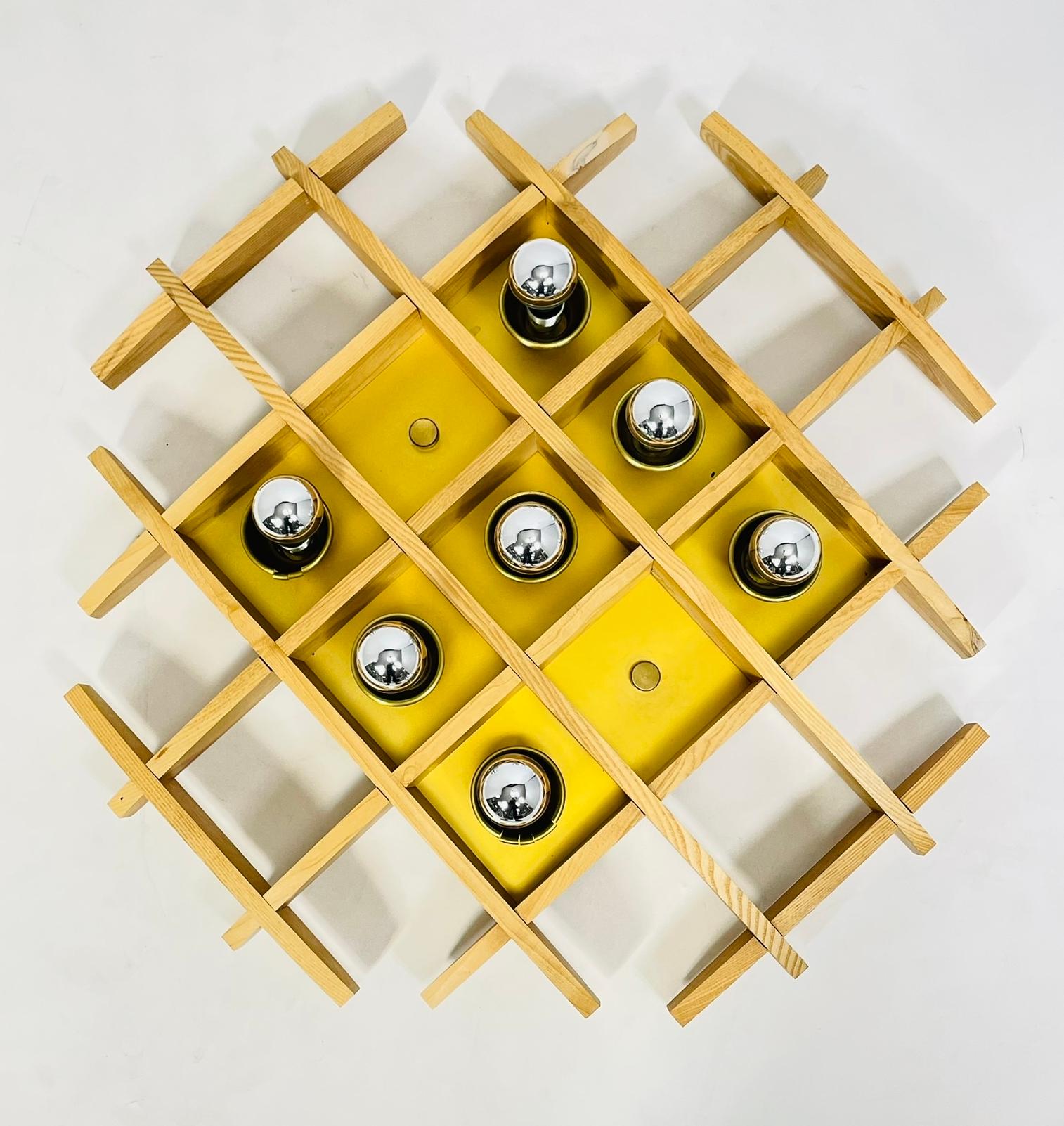 Straordinaria lampada da incasso (o da parete) italiana degli anni '70 attribuita ad Angelo Brotto.
Un reticolo scultoreo in legno (probabilmente frassino) forma A una griglia a cupola poco profonda su un pannello centrale giallo zafferano dotato di