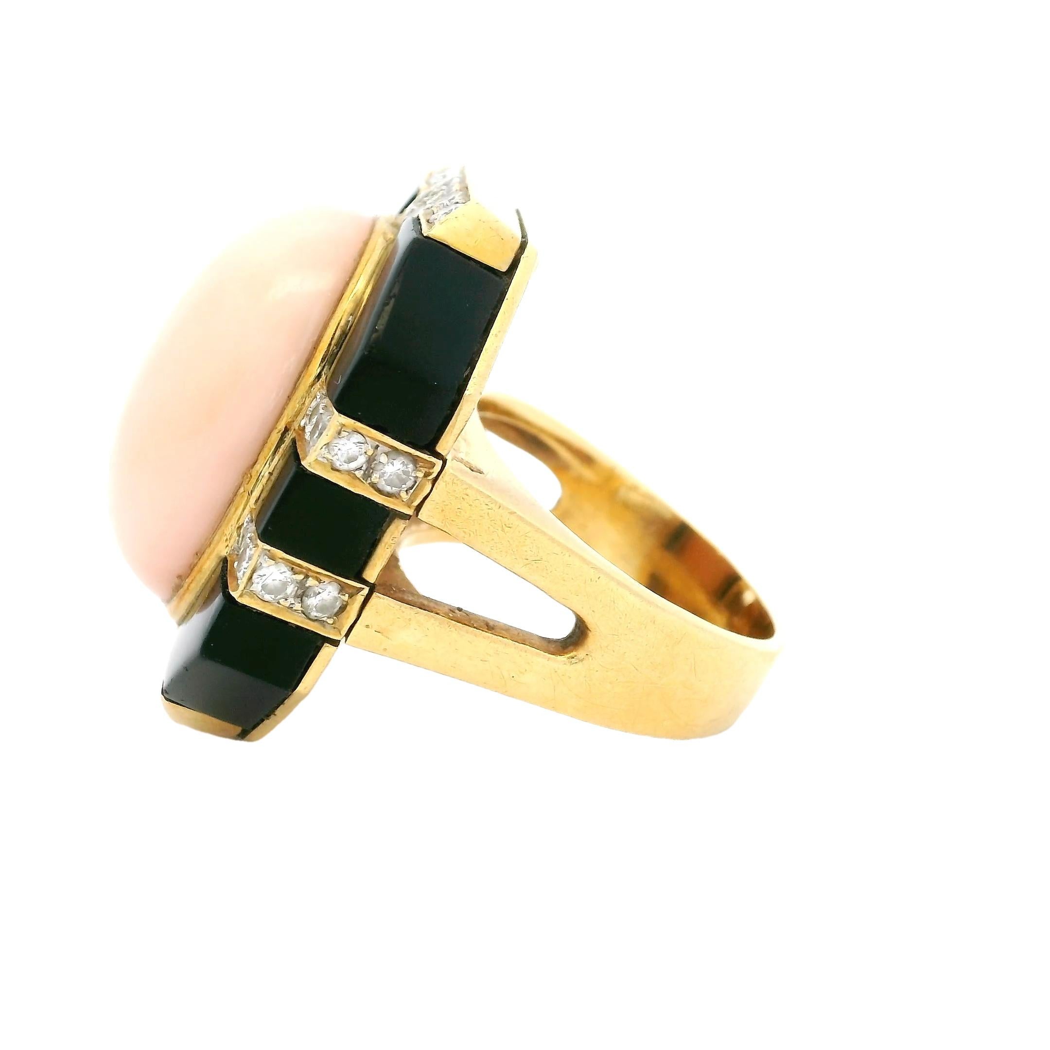 Ein spektakulärer italienischer Vintage-Ring aus den 1980er Jahren, der meisterhaft aus 18 Karat Gelbgold gefertigt und als kühnes Statement entworfen wurde. In der Mitte liegt eine exquisite ovale Cabochon-Koralle, deren sanfter Rot-Ton Wärme und